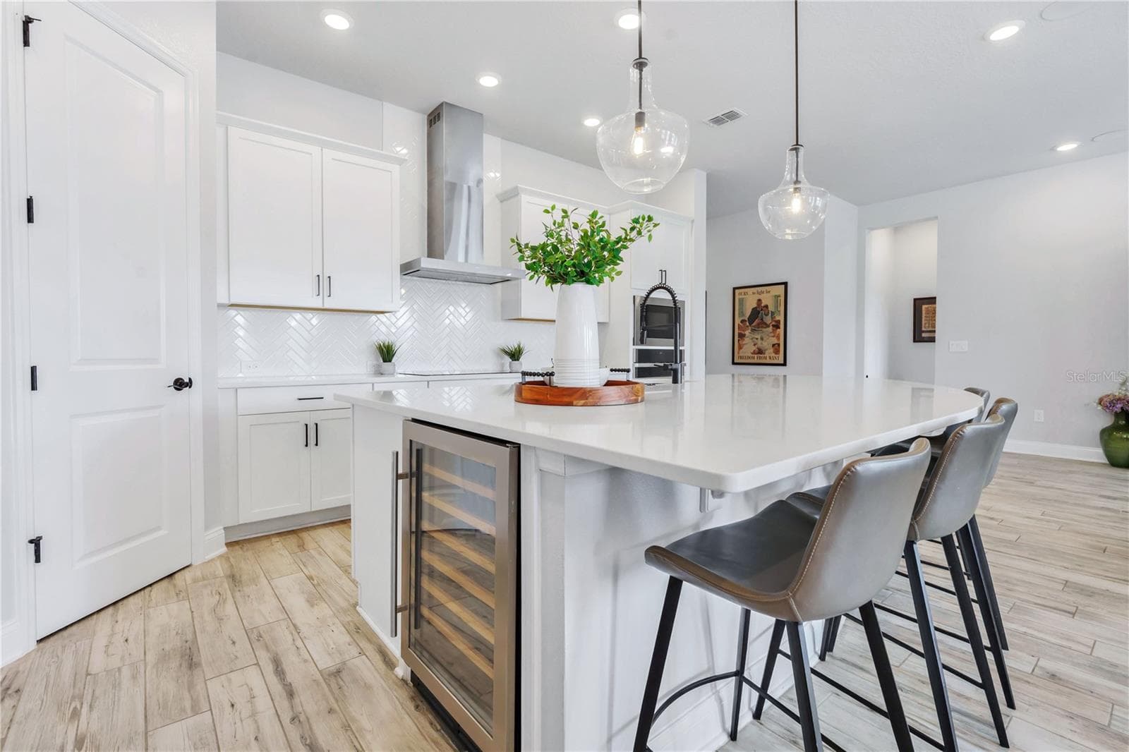 Quartz island with built in wine refrigerator, matte black hardware, and counter seating. A true centerpiece for hosting. - 8336 CANETTI ST, ORLANDO