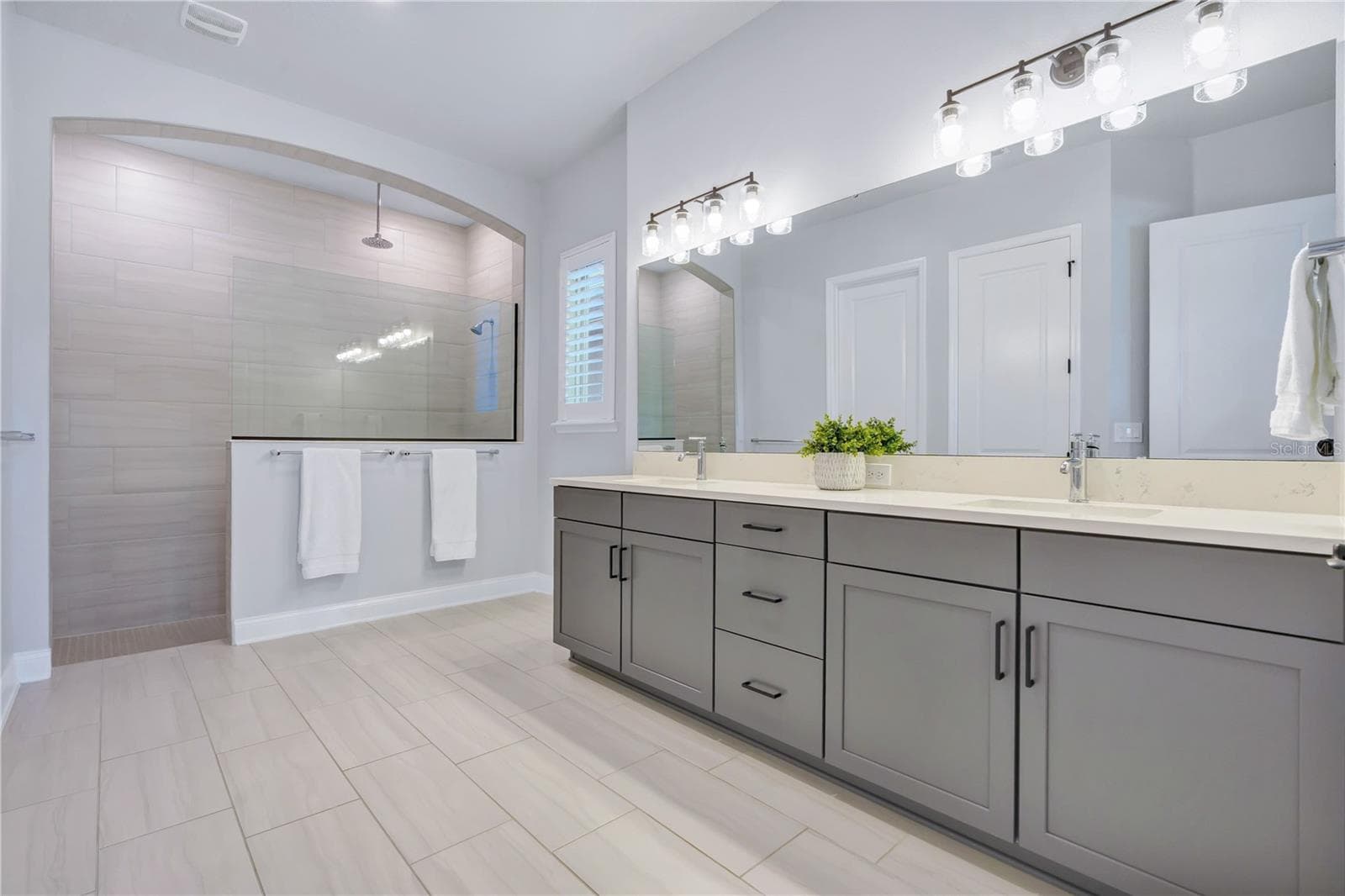 Primary bath with a Carrara Marmi quartz double vanity, extra drawer storage, and a large walk in shower. - 8336 CANETTI ST, ORLANDO