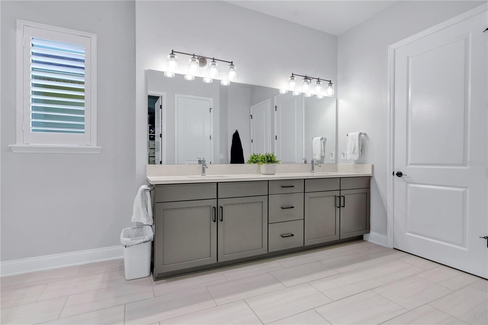 Primary bath vanity with dual sinks, quartz counters, framed mirrors, and modern lighting. - 8336 CANETTI ST, ORLANDO