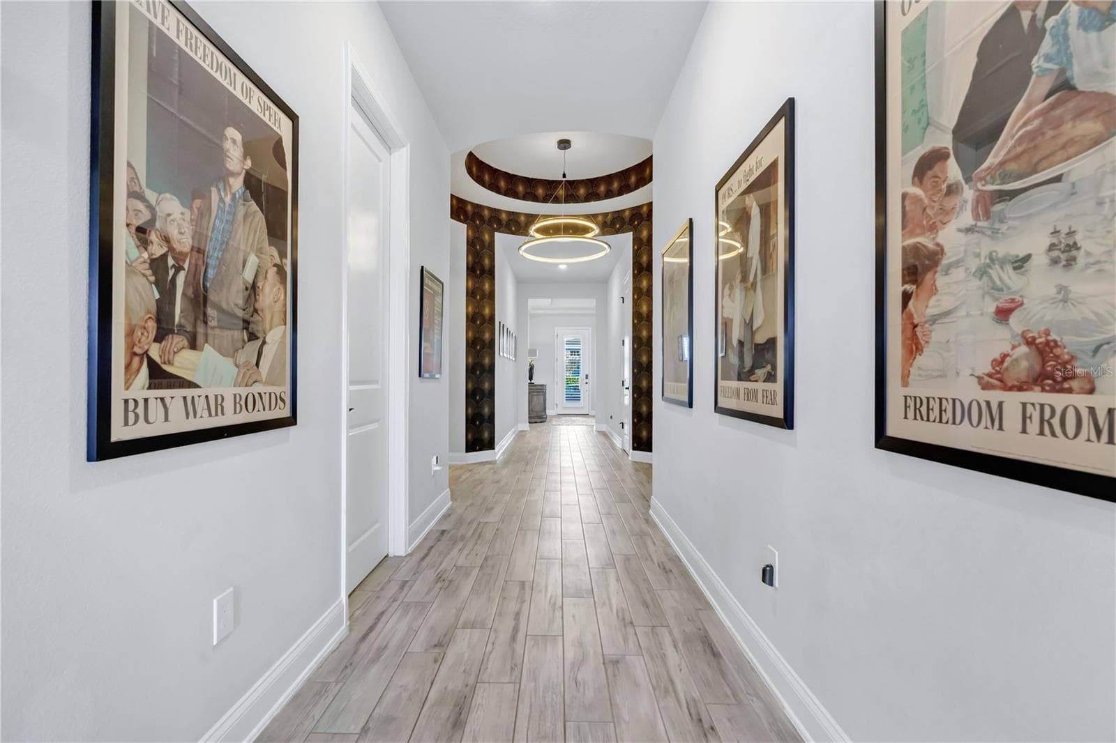 Gallery style entry hallway with wood look plank tile, wide baseboards, and crown moulding welcoming you inside. - 8336 CANETTI ST, ORLANDO