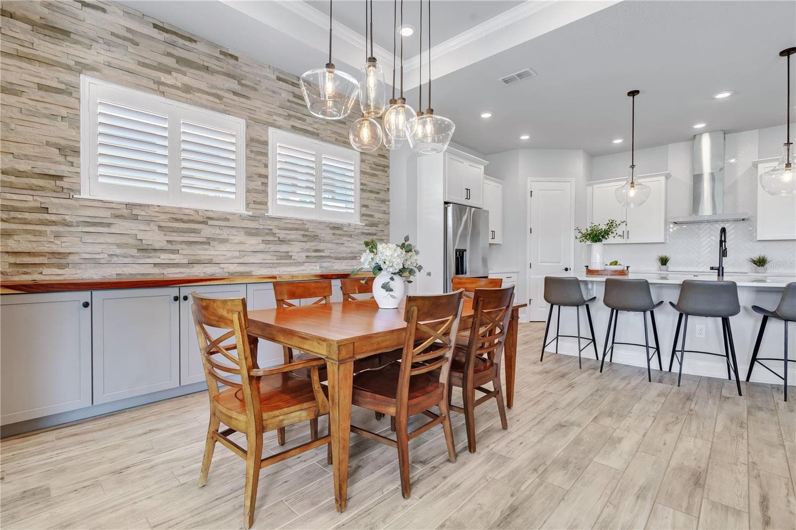 Dining area with a stone accent wall and modern chandelier, steps from the kitchen. Ideal for dinners at home in Lake Nona. - 8336 CANETTI ST, ORLANDO