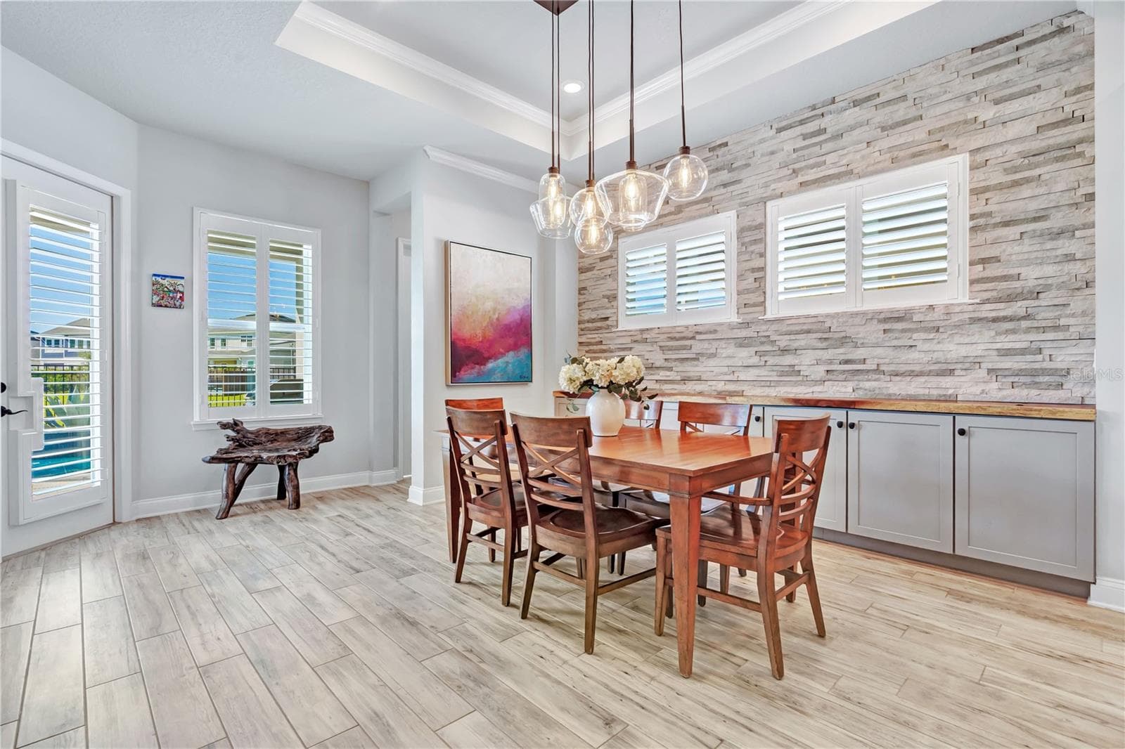 Dining space with natural light and stone accent wall, open to the kitchen and living areas. - 8336 CANETTI ST, ORLANDO