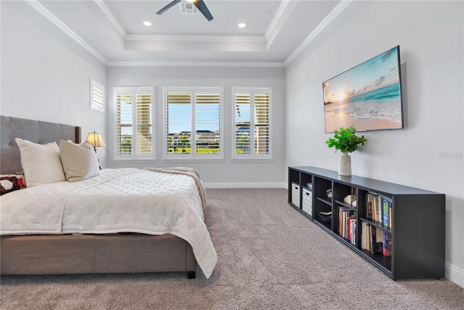 Primary bedroom with tray ceiling, ceiling fan, and plantation shutters. - 8336 CANETTI ST, ORLANDO