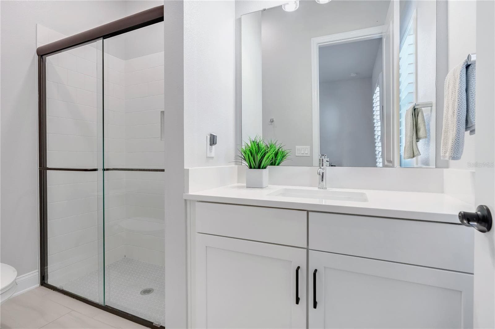 Secondary bath with walk in shower with tile to the ceiling, ceiling mounted rain shower head, and hex mosaic floor. - 8336 CANETTI ST, ORLANDO