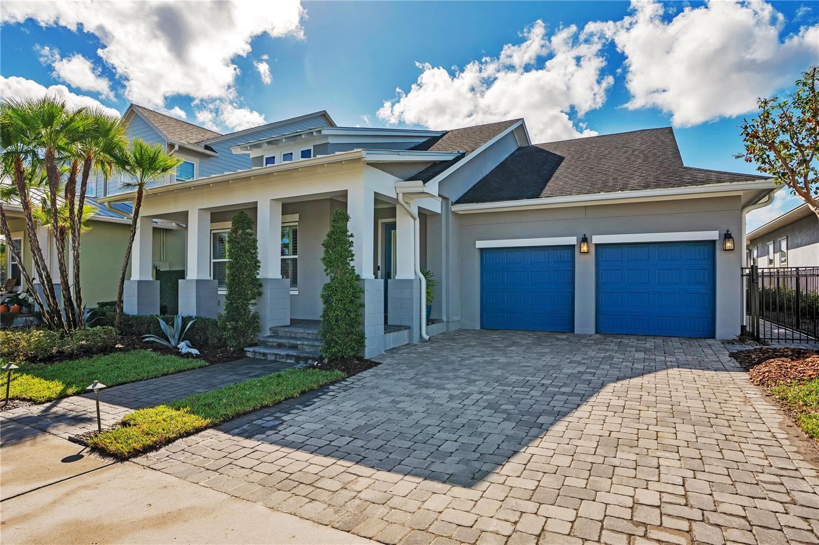 Front elevation with paver driveway, two car garage with EV charging, and covered front porch. - 8336 CANETTI ST, ORLANDO