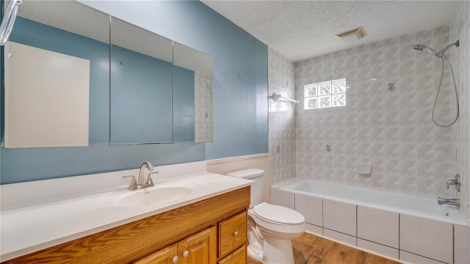 The 2nd bath features wood cabinetry, a large built-in medicine cabinet, and a tiled shower surround. - 909 SE 27TH ST, CAPE CORAL