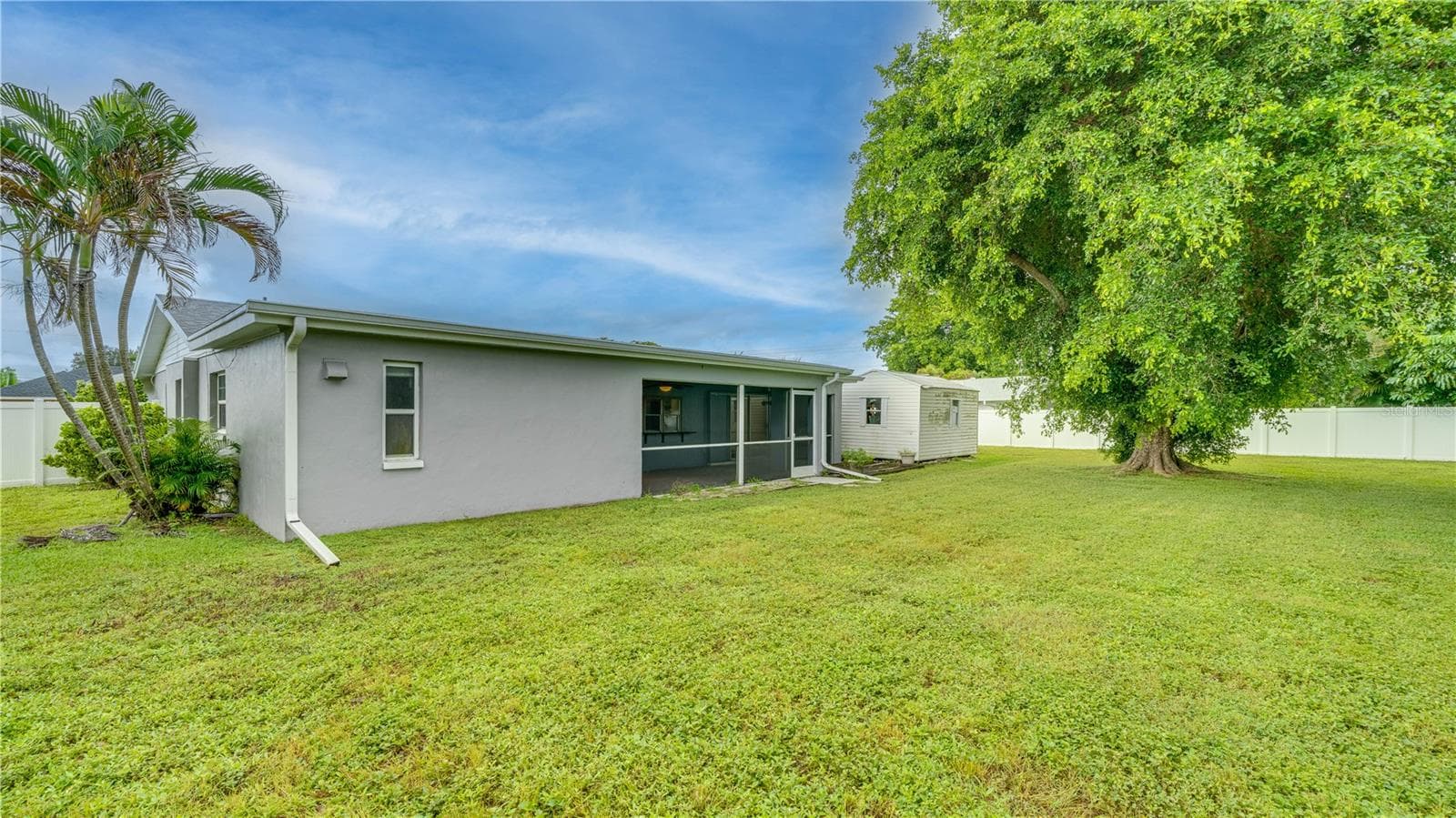 Enjoy the expansive 3-lot backyard with mature landscaping, a new white privacy fence, and a detached storage shed. - 909 SE 27TH ST, CAPE CORAL