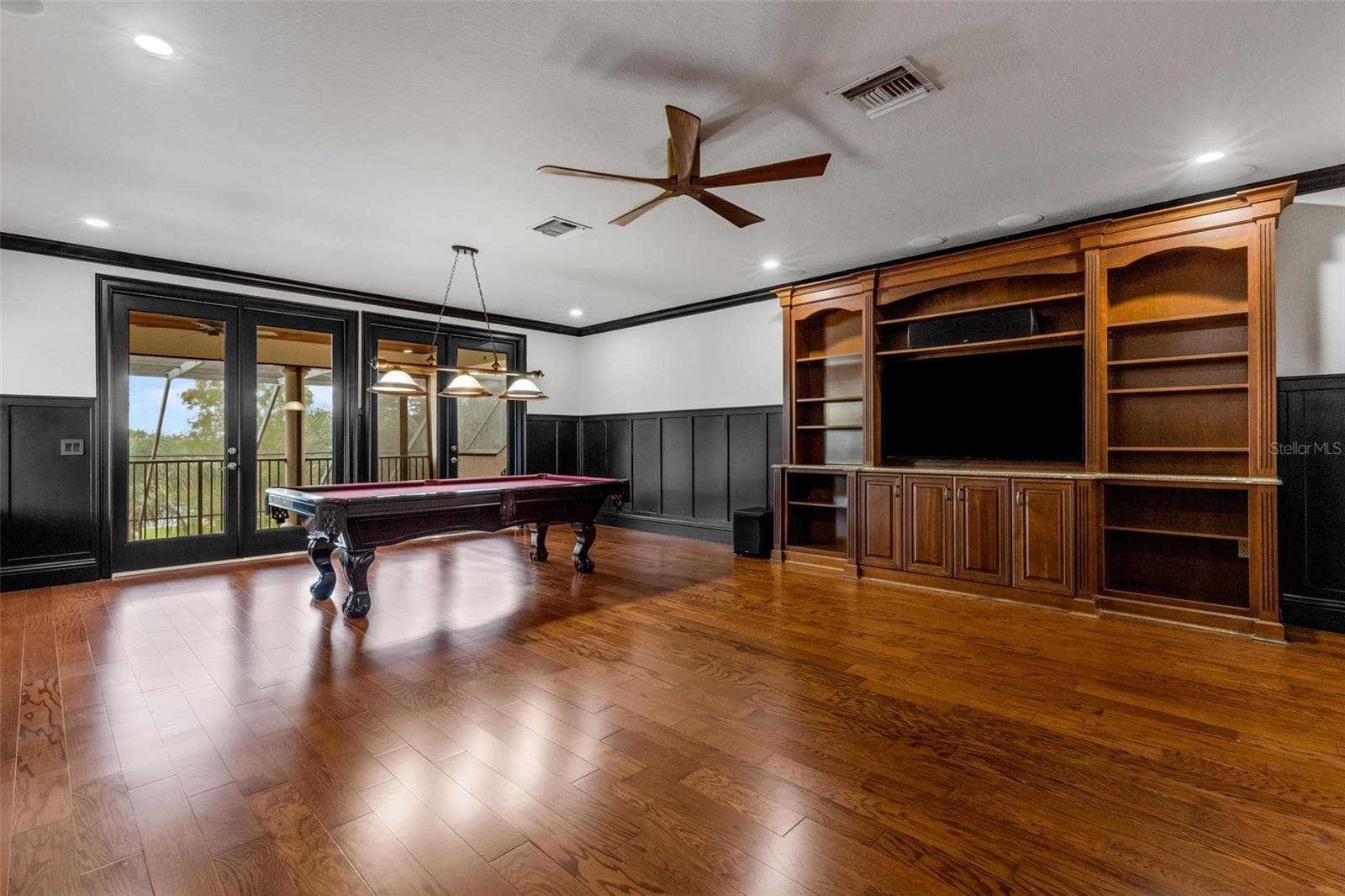 The built-in entertainment system, custom wainscoting all around and two sets of glass doors that open to the balcony. - 2734 BELLERIVE DR, LAKELAND