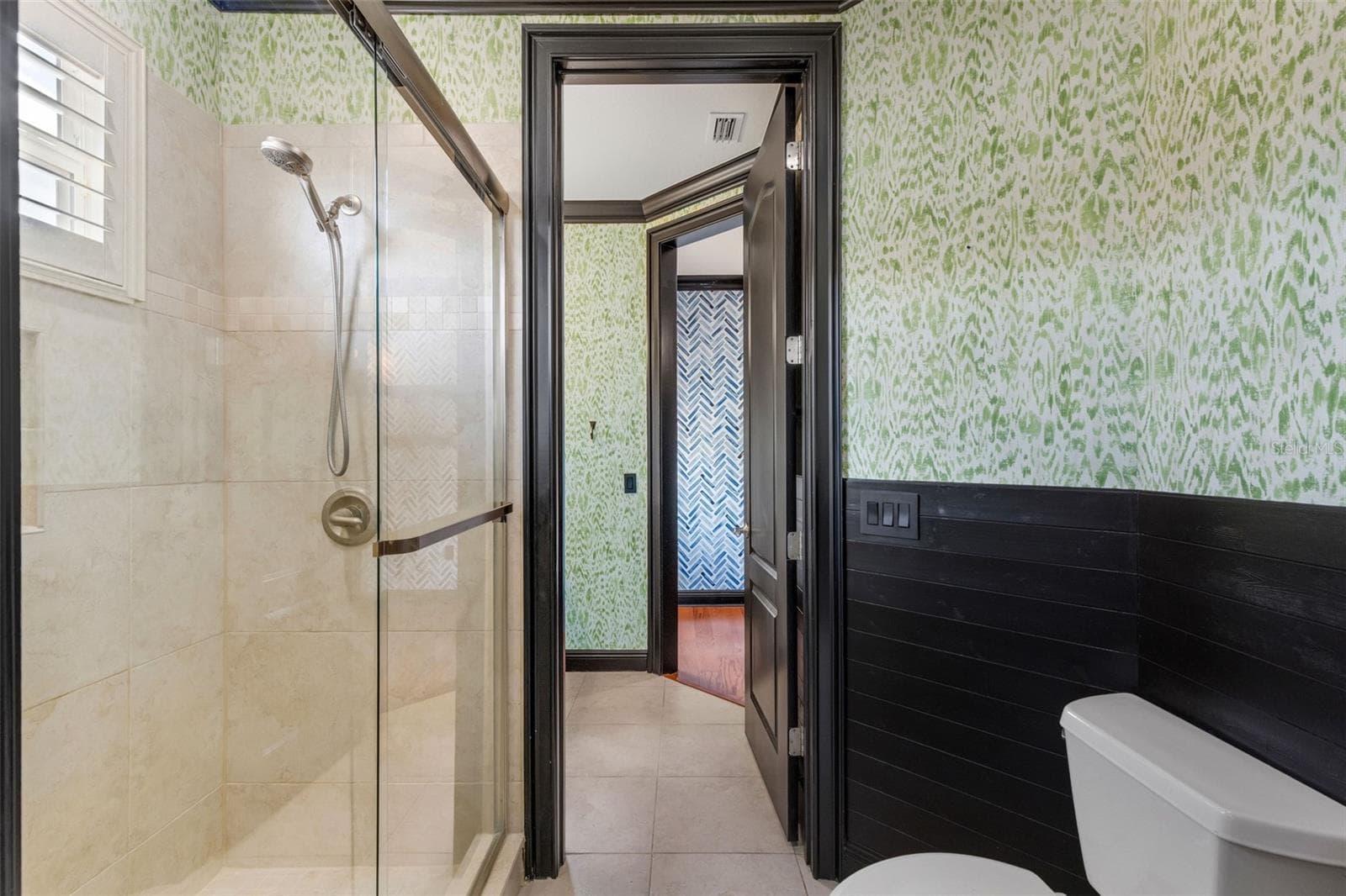 The shared part of this bathroom has a fully tiled shower with custom glass enclosure. - 2734 BELLERIVE DR, LAKELAND