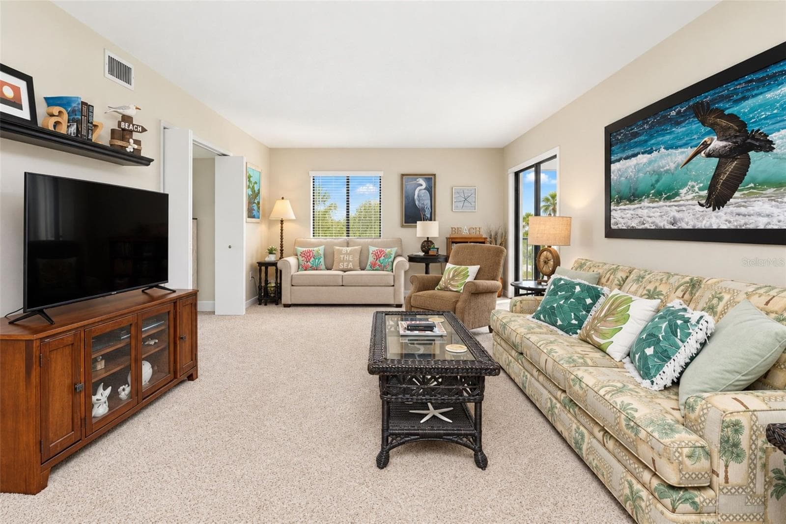 The living room has carpeted flooring and sliding glass doors to the lanai. - 2950 N BEACH RD #A321, ENGLEWOOD