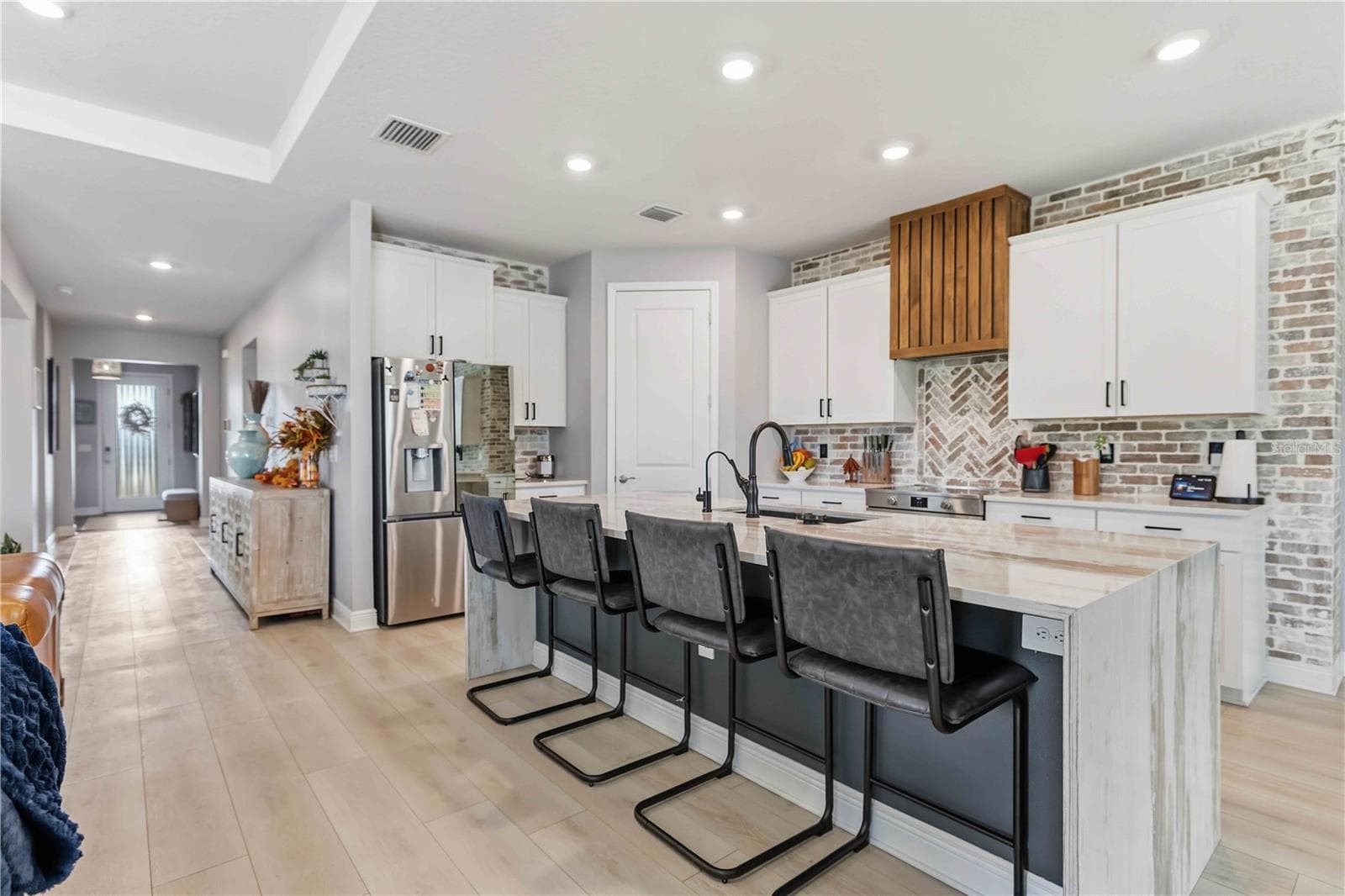 kitchen with waterfall quartz island, custom hood vent & brick backsplash - 17604 BARLEY DR, LAKEWOOD RANCH