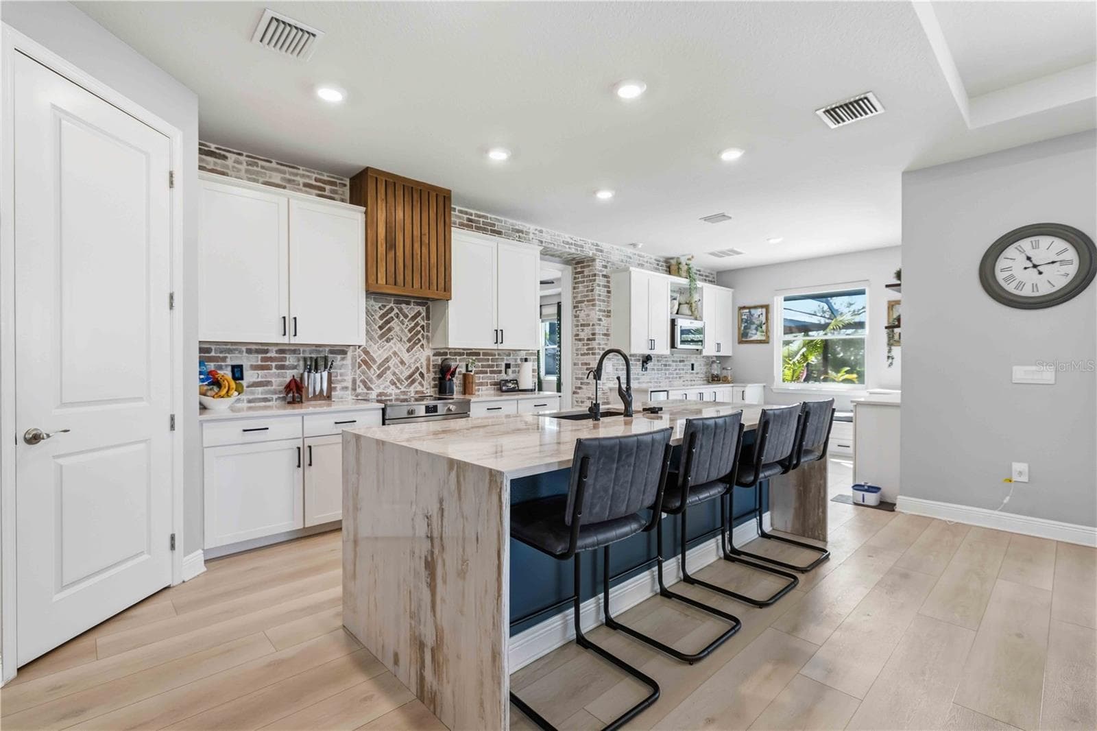 kitchen with waterfall quartz island, custom hood vent & brick backsplash - 17604 BARLEY DR, LAKEWOOD RANCH