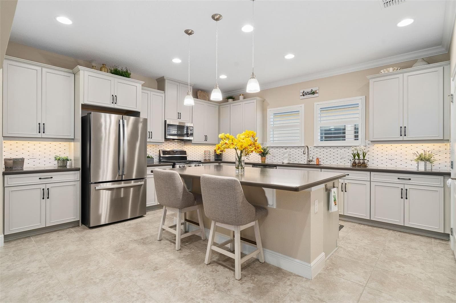 What a Beautiful Kitchen with a Natural Stone Backsplash, Pendant Lighting, Quartz Countertops, Upgraded Stainless Steel Appliances and Plantation Shutters. - 2607 CLEMSON RIDGE CT, CLERMONT