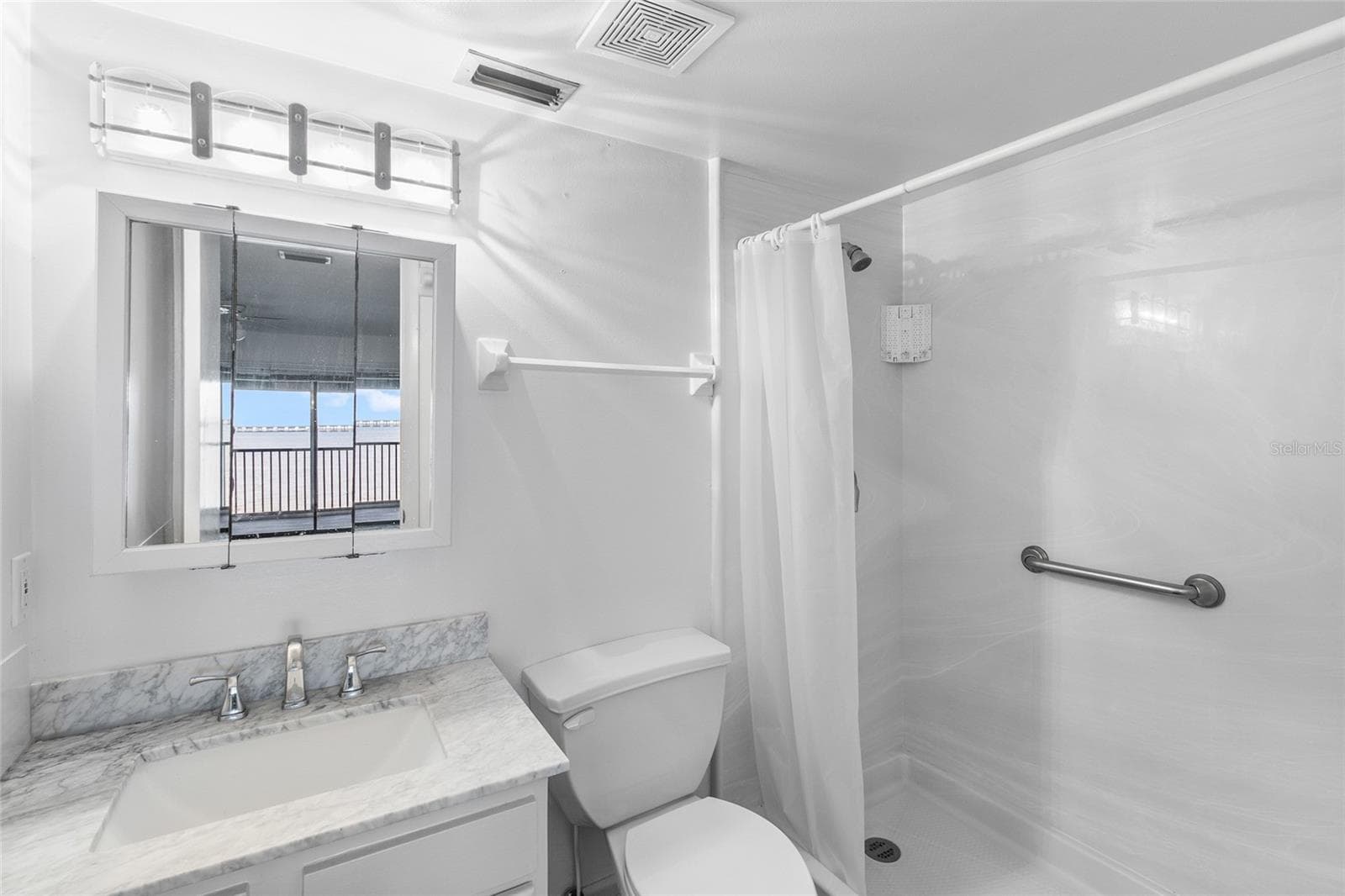 Primary bath with step in shower - water view seen in mirror - 2980 HAINES BAYSHORE RD #105, CLEARWATER