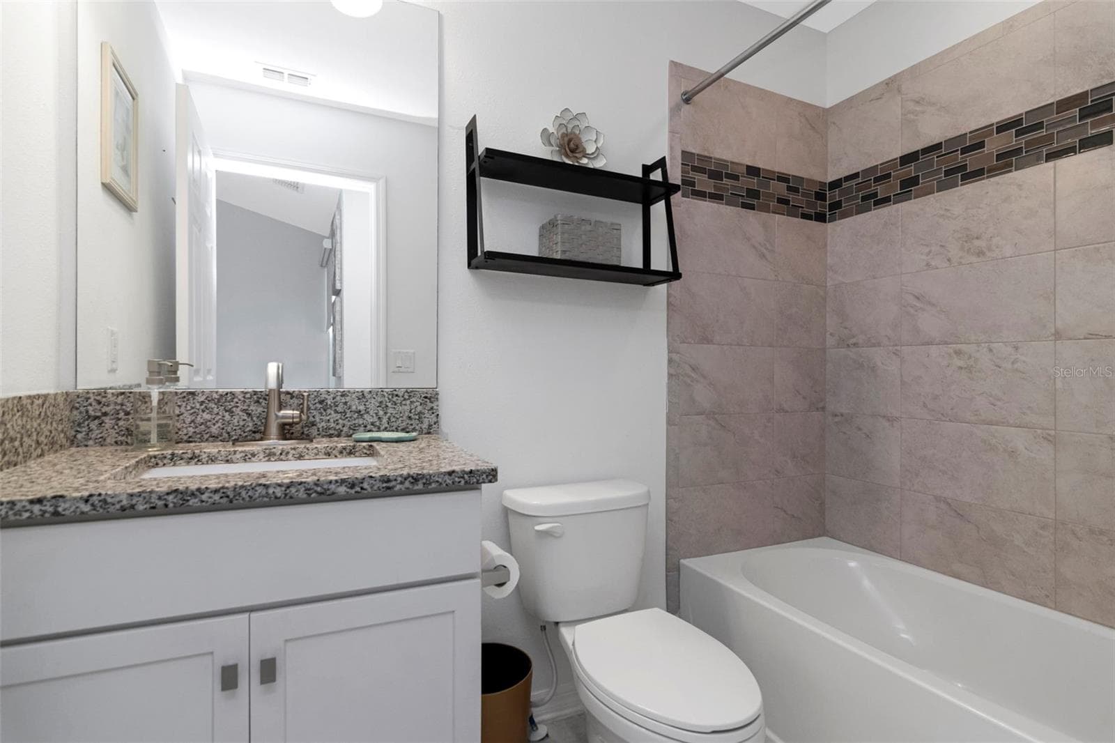 Second bathroom featuring a granite countertop and tiled tub/shower combination - 2455 GOLDEN PASTURE CIR, CLEARWATER