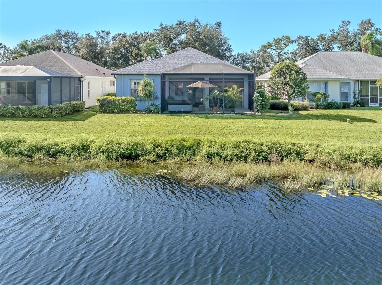 A lovely backyard setting with peaceful lake views, creating the perfect backdrop for relaxing and enjoying the beauty of Florida living! - 443 BERMUDA ISLES CIR, VENICE