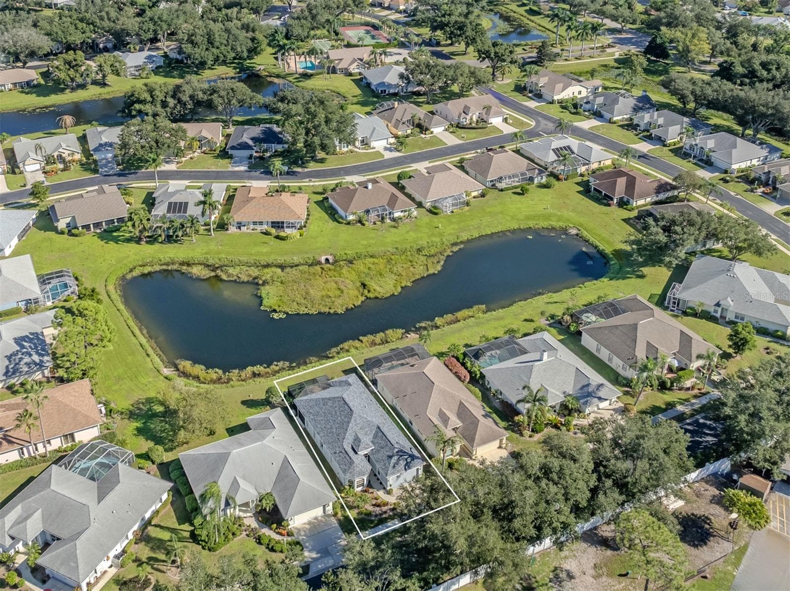 A bird’s-eye view of this lovely neighborhood, showcasing the home's beautiful setting, sparkling lake, and picturesque surroundings in the Isles of Chestnut Creek! - 443 BERMUDA ISLES CIR, VENICE