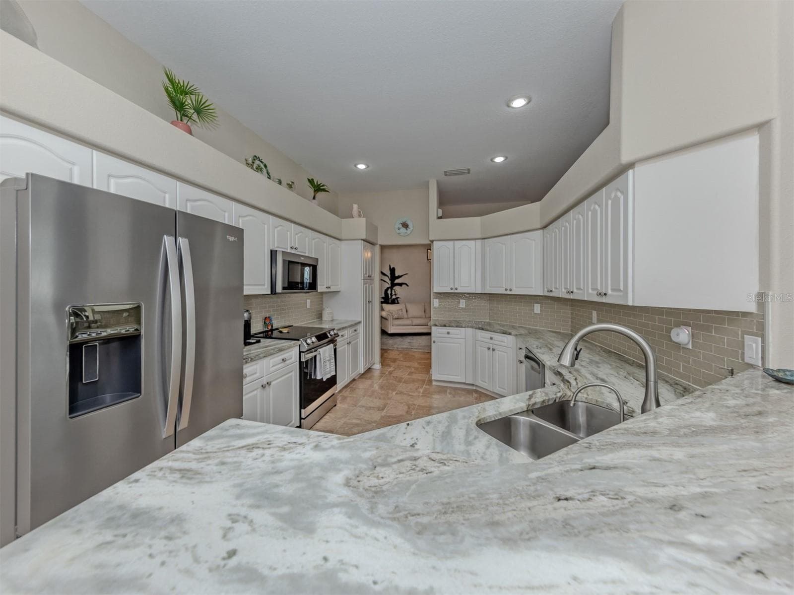 A spacious, beautifully updated kitchen featuring gorgeous granite countertops, crisp white cabinetry, sleek stainless steel appliances, and recessed lighting with dimmer controls to create the perfect ambiance for cooking, gathering, and entertaining! - 443 BERMUDA ISLES CIR, VENICE