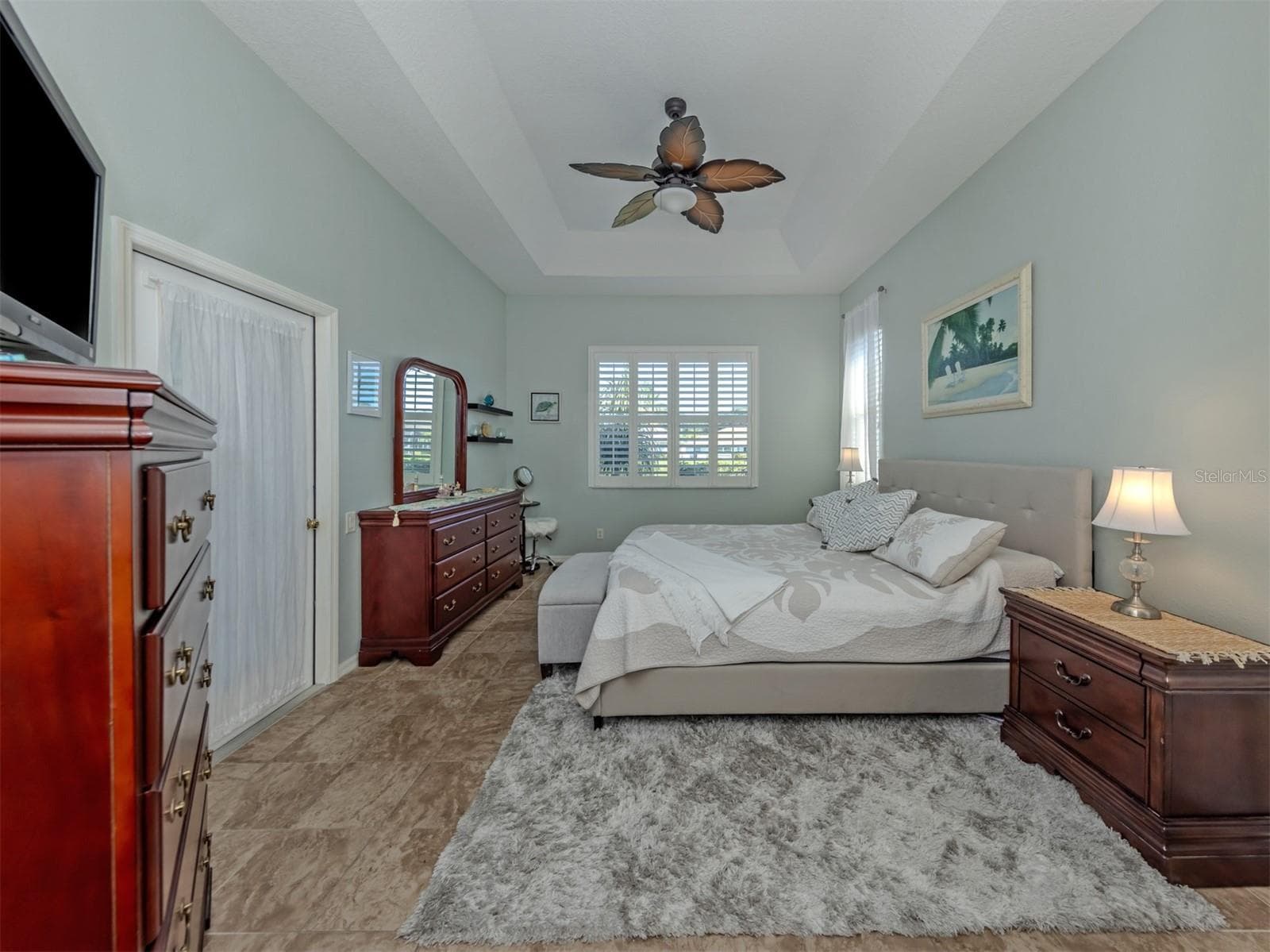 Your own private slice of paradise! This beautiful primary suite is a delightful retreat, featuring an elegant tray ceiling, ceiling fan, gorgeous ceramic tile flooring that flows seamlessly throughout the home, and lovely lake views! Step directly onto the extended lanai to enjoy the Florida sunshine, while two closets, including a generous walk-in, provide plenty of room for your wardrobe! - 443 BERMUDA ISLES CIR, VENICE