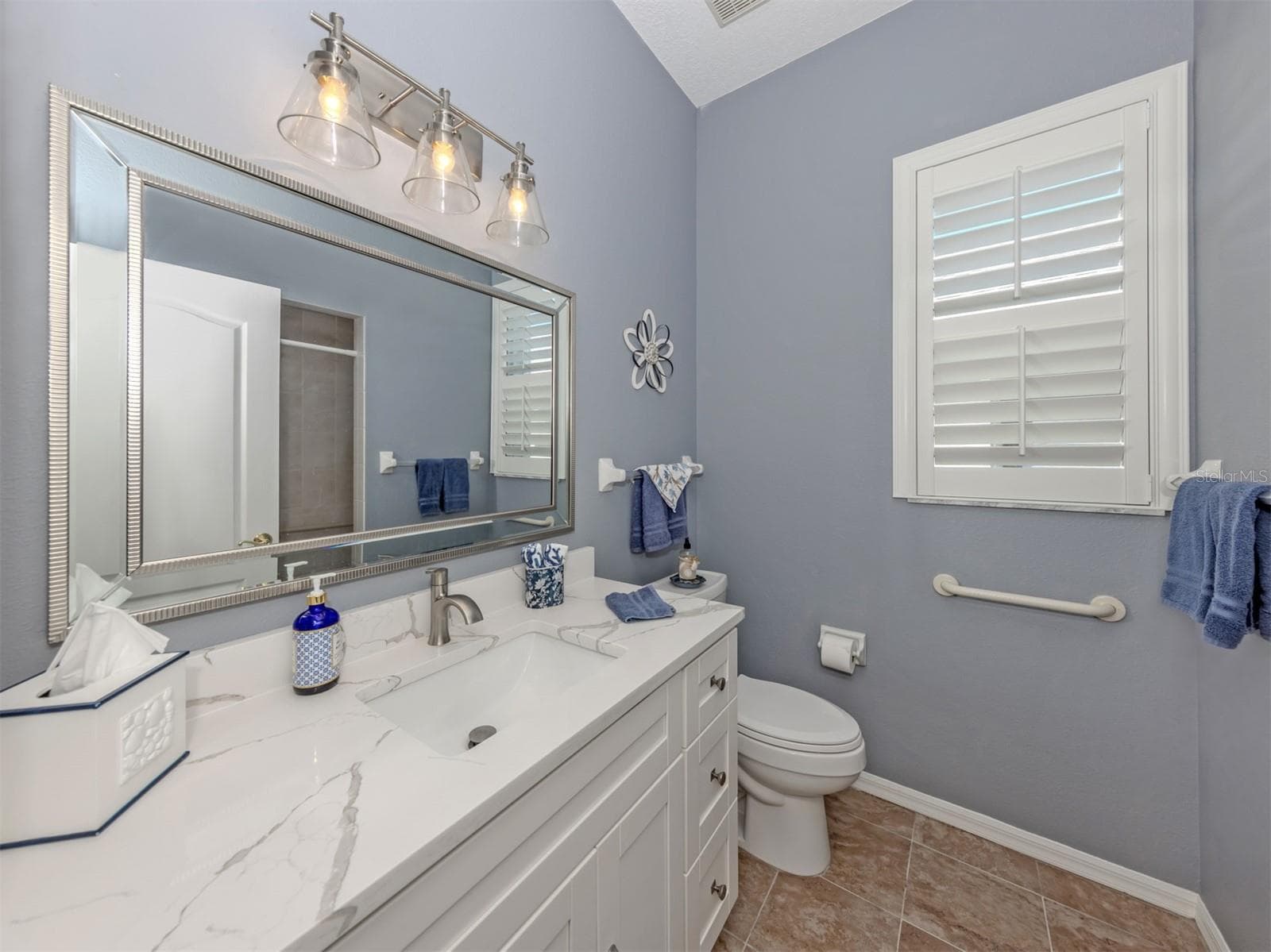 A little luxury for everyone! This beautifully updated guest bathroom shines with a gorgeous quartz countertop, stylish new lighting, a lovely new mirror, and a refreshing walk-in shower. A delightful blend of elegance and comfort, perfectly situated to serve both guest bedrooms and visiting friends and family! - 443 BERMUDA ISLES CIR, VENICE