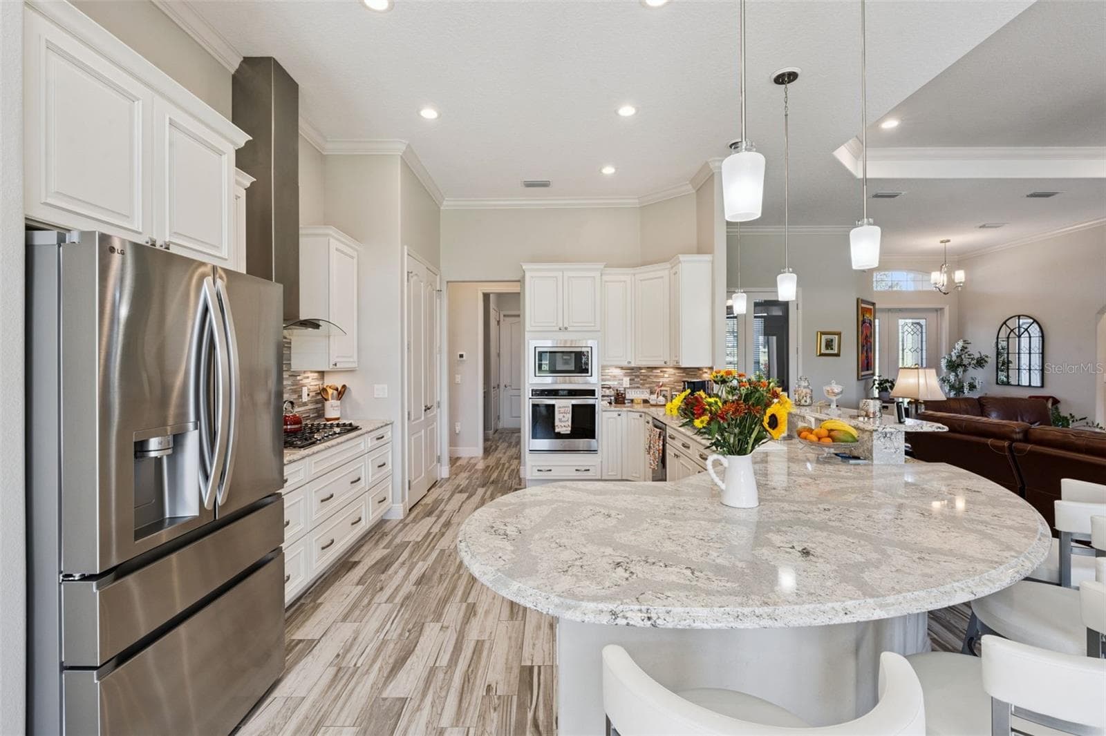 Designer kitchen featuring high-end stainless steel appliances, including a professional-grade gas cooktop, built-in wall oven, and a sleek modern vent hood. - 36819 WOLF CT, EUSTIS