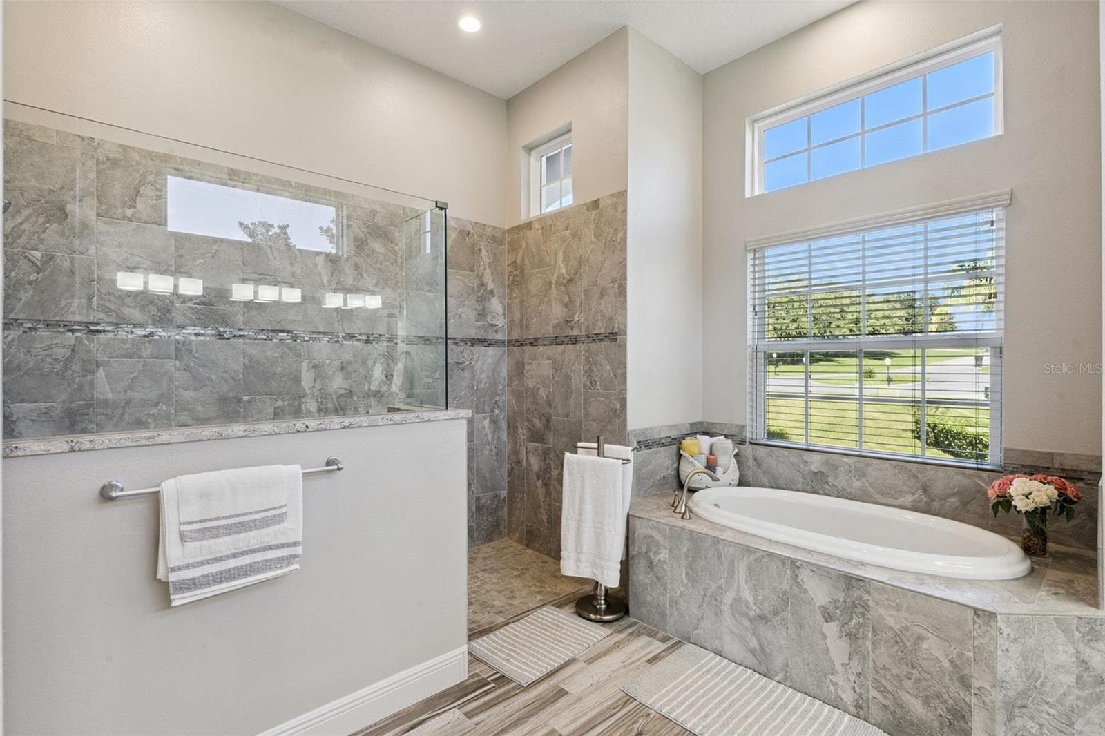 Spacious master en suite featuring a luxurious, zero-entry walk-in shower and a deep soaking tub for ultimate relaxation. - 36819 WOLF CT, EUSTIS