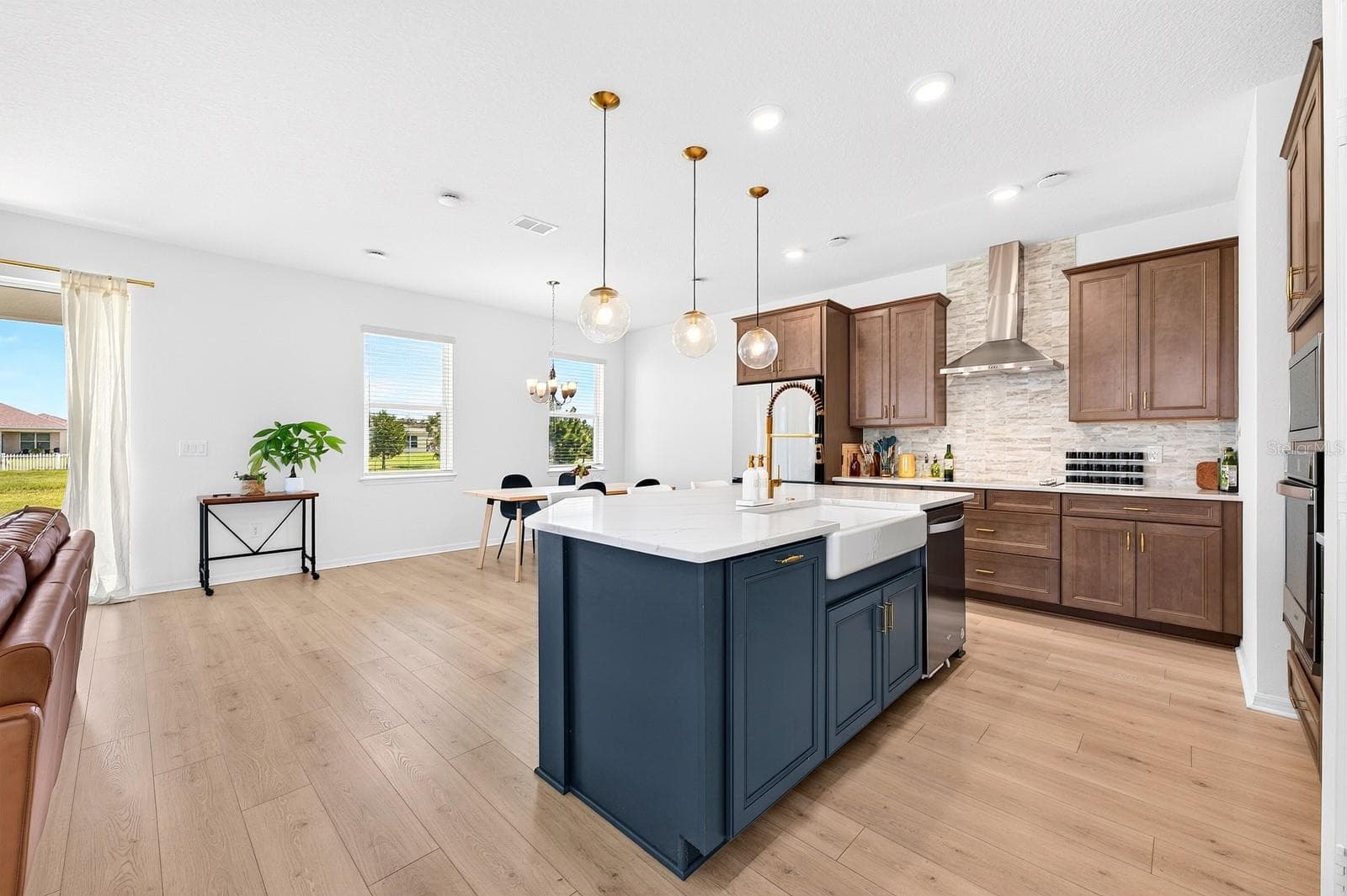 The Kitchen features a stylish Belfast sink that adds a touch of timeless character, beautifully complementing the quartz countertops, modern backsplash and sleek contemporary finishes. - 1785 PETIOLE PL, KISSIMMEE