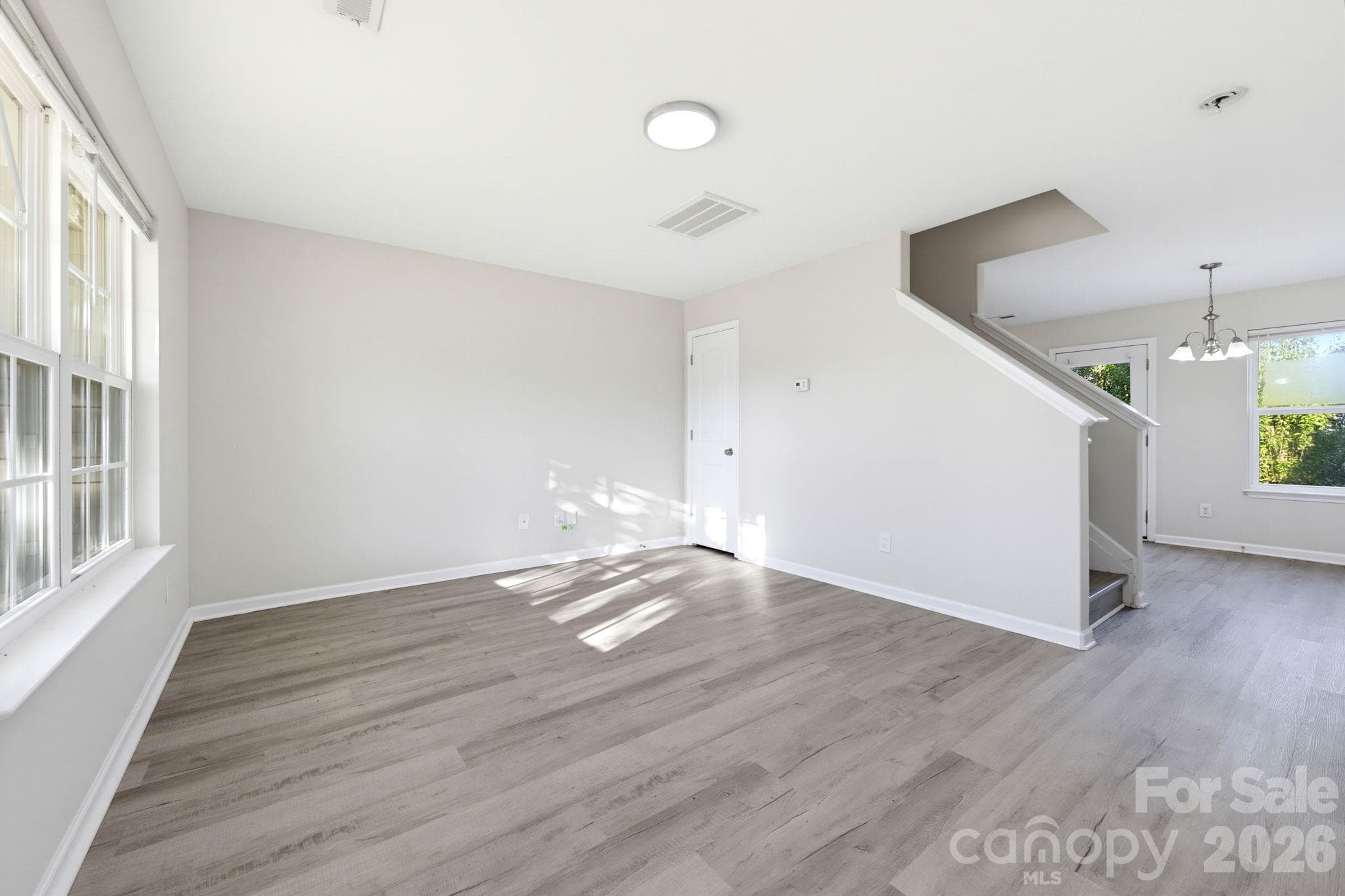 Living Room - Bright, open living area featuring modern flooring, neutral walls, and a versatile layout. - 5718 Natick Drive, Charlotte