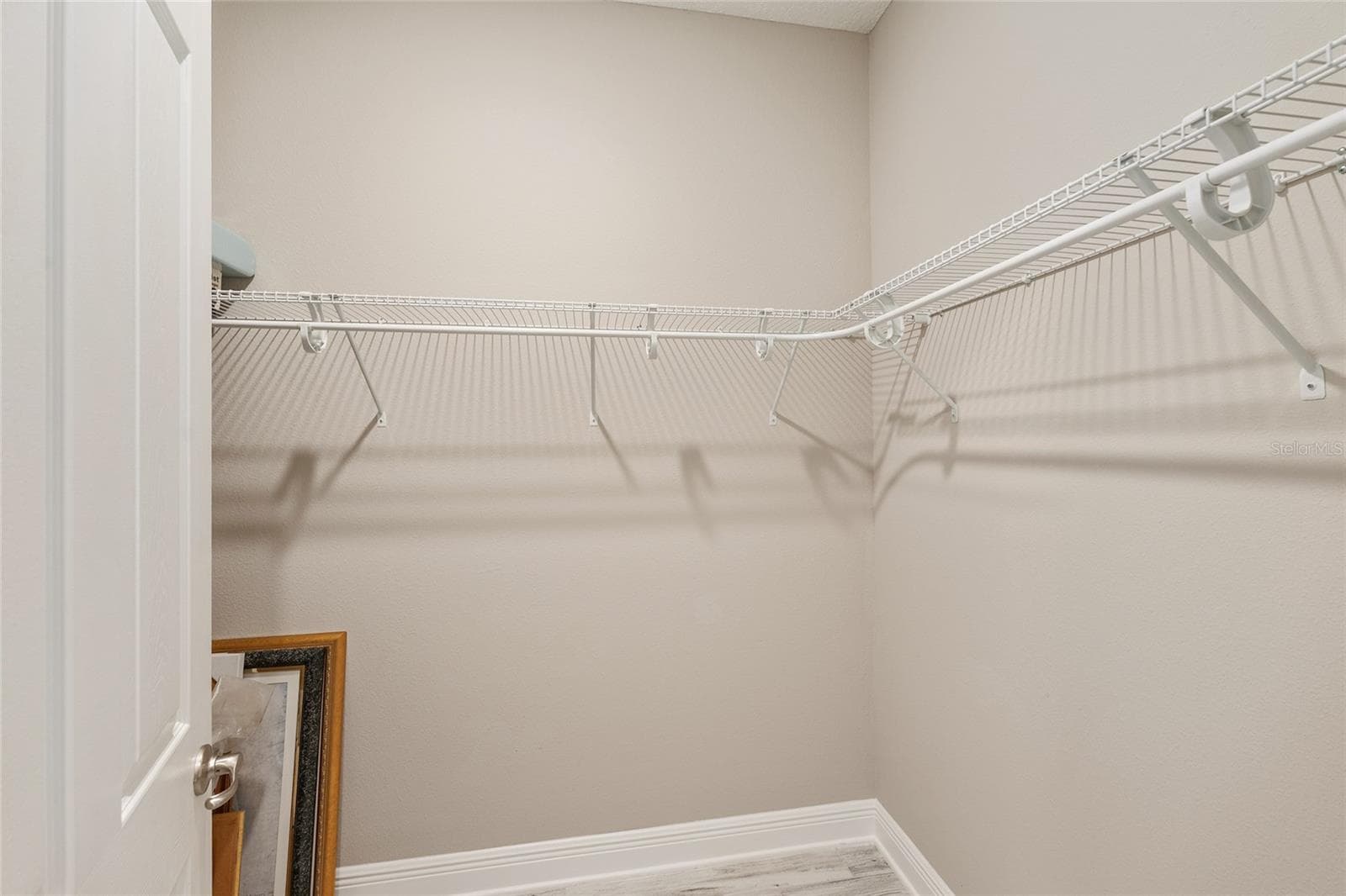 Second primary suite's spacious walk-in closet features wraparound shelving and ample hanging space, providing practical storage and organization. - 8290 SW 92ND CIR, OCALA