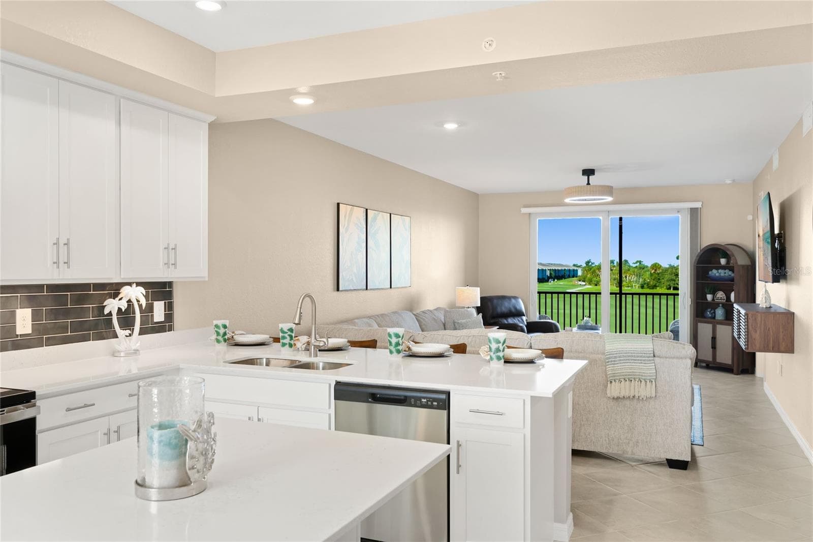 Open floor plan featuring a spacious kitchen with abundant counter space for meal preparation and ample seating, ideal for cooking and entertaining, all overlooking the living area with beautiful golf course, water, and preserve views. - 17565 OPAL SAND DR #204, VENICE