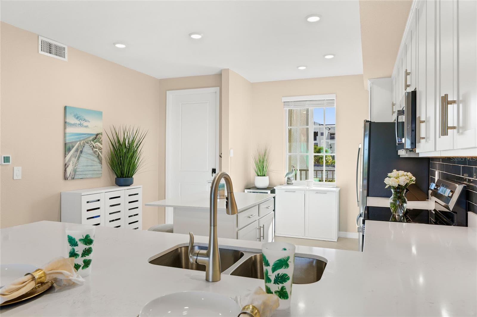 Open floor plan featuring a spacious kitchen with abundant counter space for meal preparation and ample seating, ideal for cooking and entertaining, all overlooking the living area with beautiful golf course, water, and preserve views. - 17565 OPAL SAND DR #204, VENICE