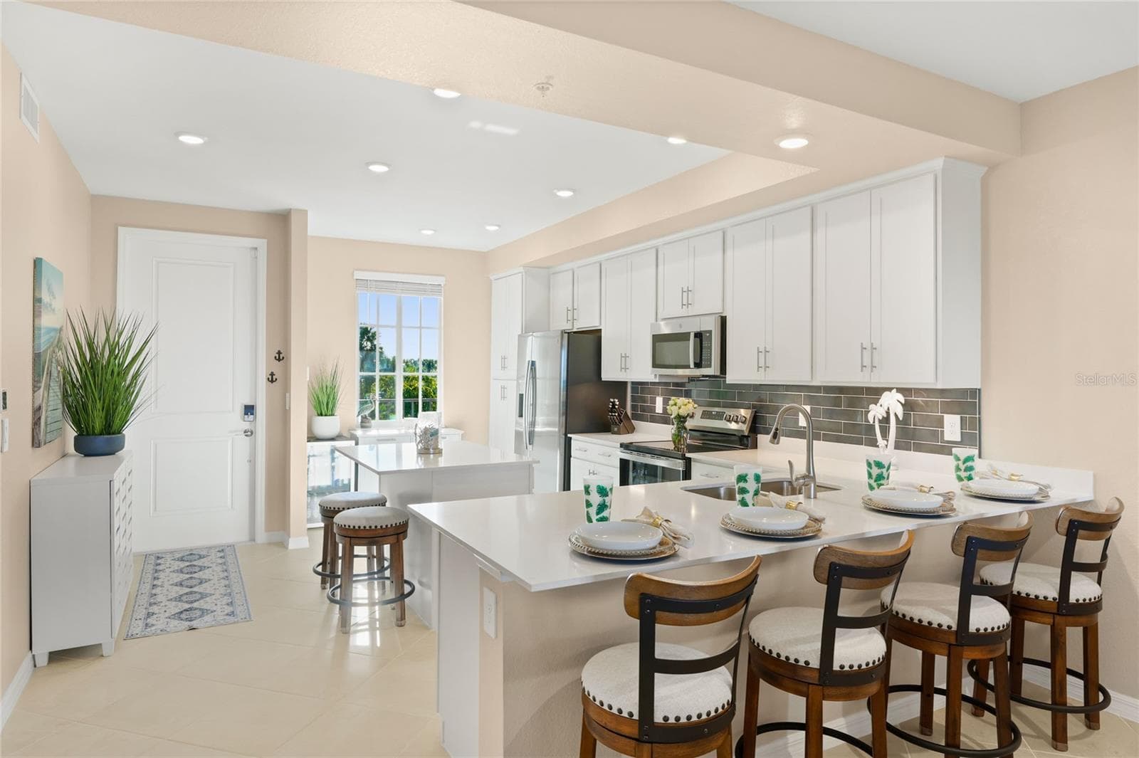 Open floor plan featuring a spacious kitchen with abundant counter space for meal preparation and ample seating, ideal for cooking and entertaining, all overlooking the living area with beautiful golf course, water, and preserve views. - 17565 OPAL SAND DR #204, VENICE