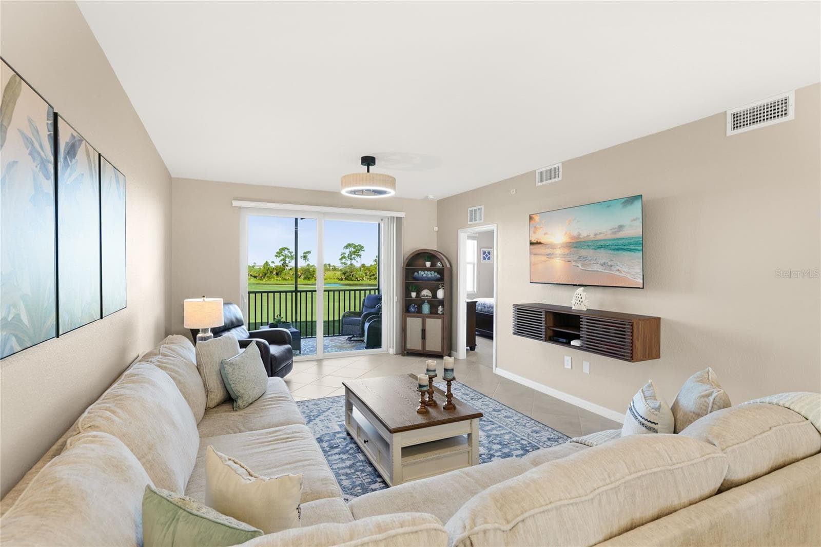 Living Room overlooking the spacious Lanai with beautiful golf course, water, and preserve views. - 17565 OPAL SAND DR #204, VENICE
