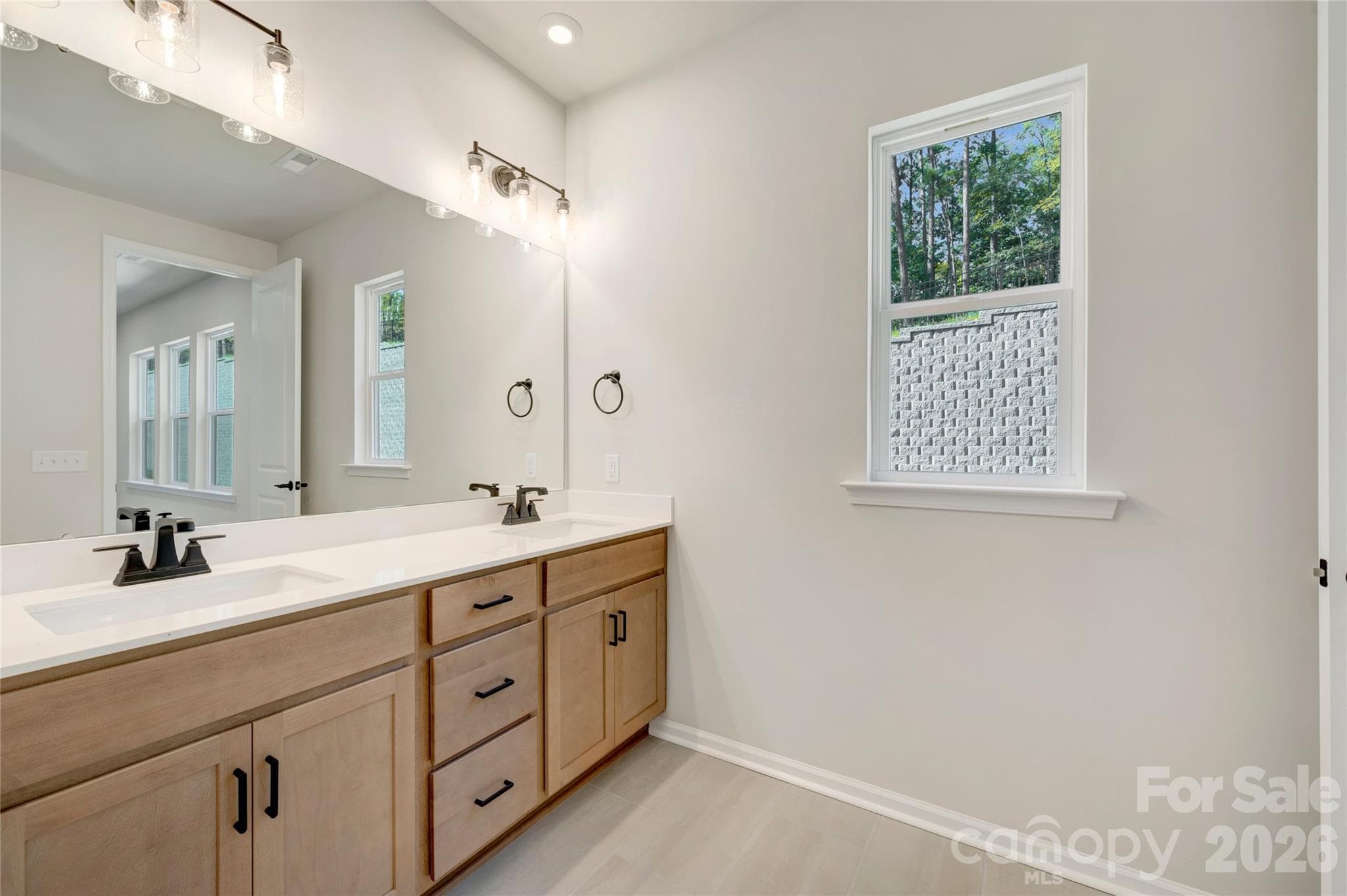 Dual vanity primary bathroom with warm brown cabinets and white quartz countertops - 707 Bowery Place, Cramerton