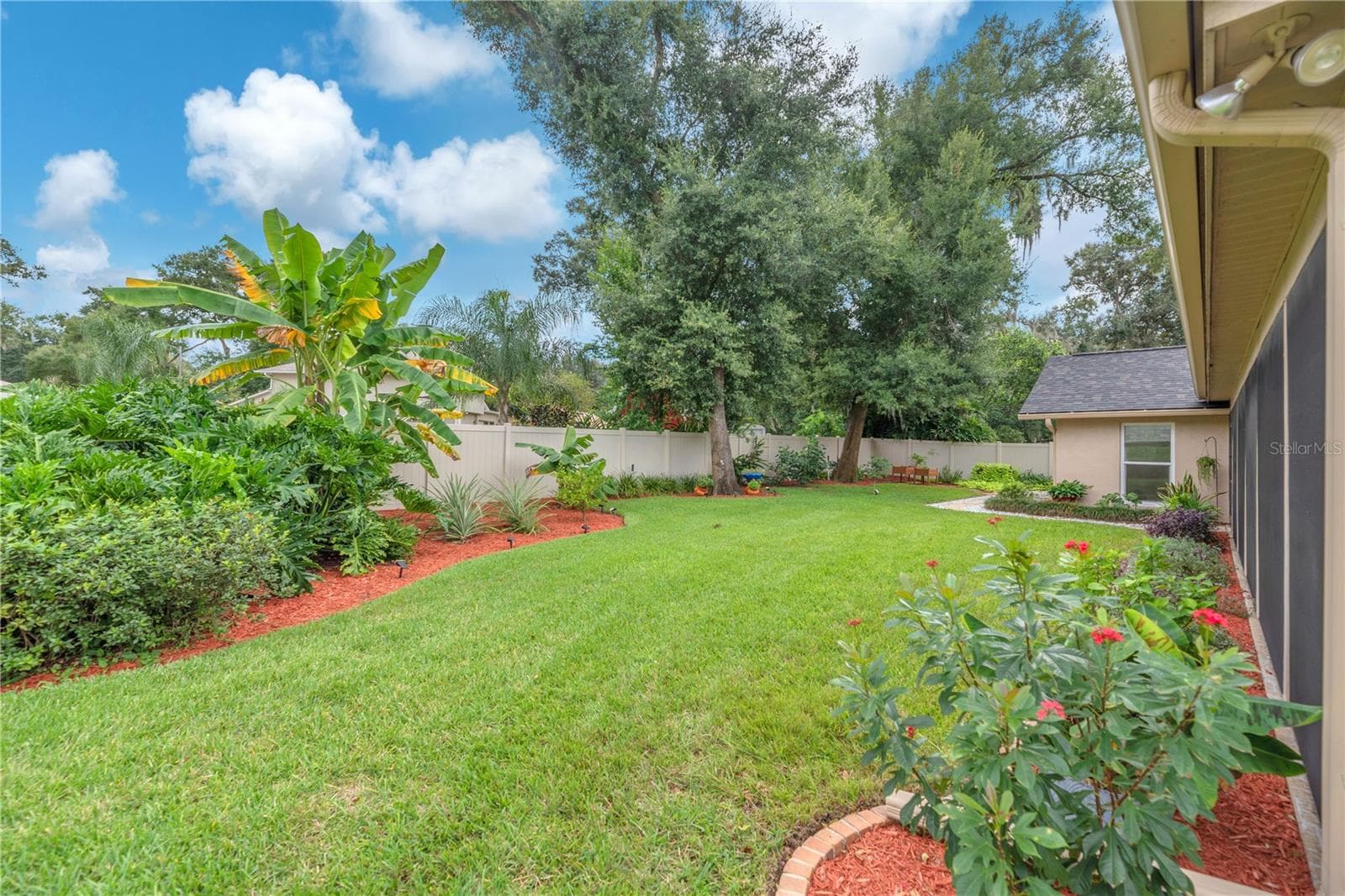 Step outside to a lushly landscaped backyard that feels like a private oasis, featuring banana, avocado, lime, and orange trees, along with pineapple plants. - 2421 OAK LANDING DR, BRANDON