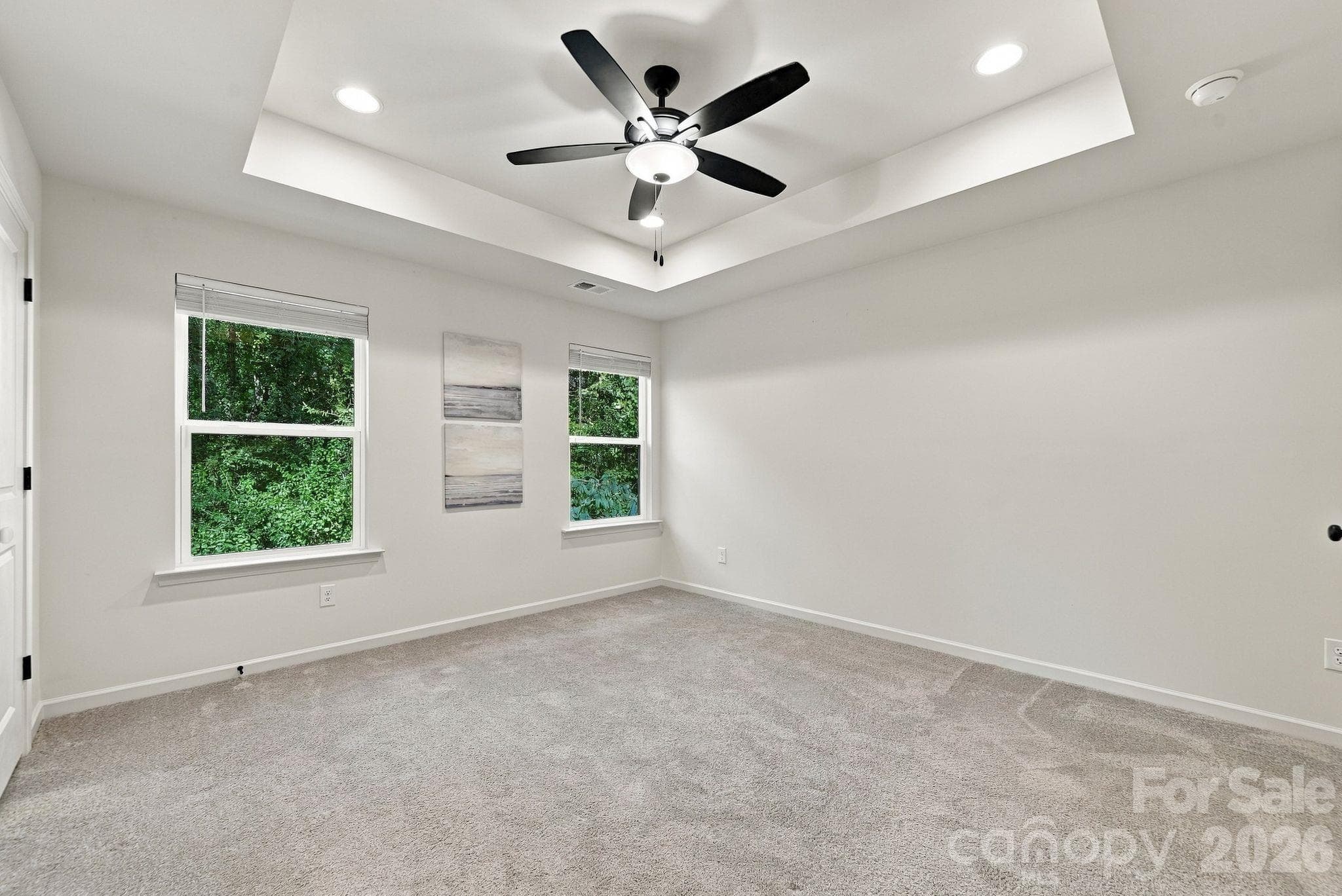 Primary bedroom with tray ceiling overlooks tree-lined yard for privacy - 4715 Crestmont Drive, Charlotte