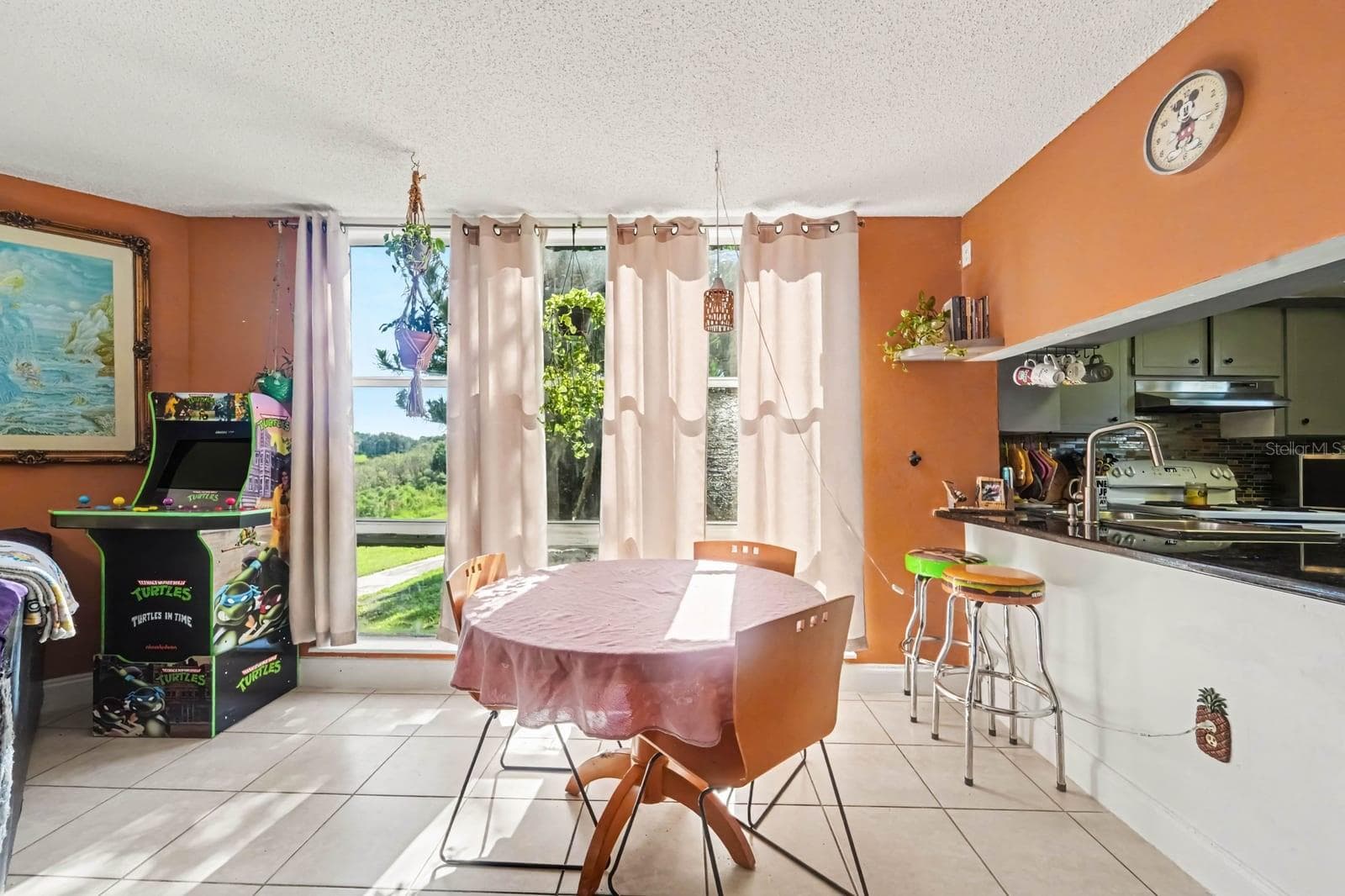 Kitchen opens to dining room with vibrant orange accent wall & sliding glass doors - 1055 ENCOURTE GREEN, APOPKA