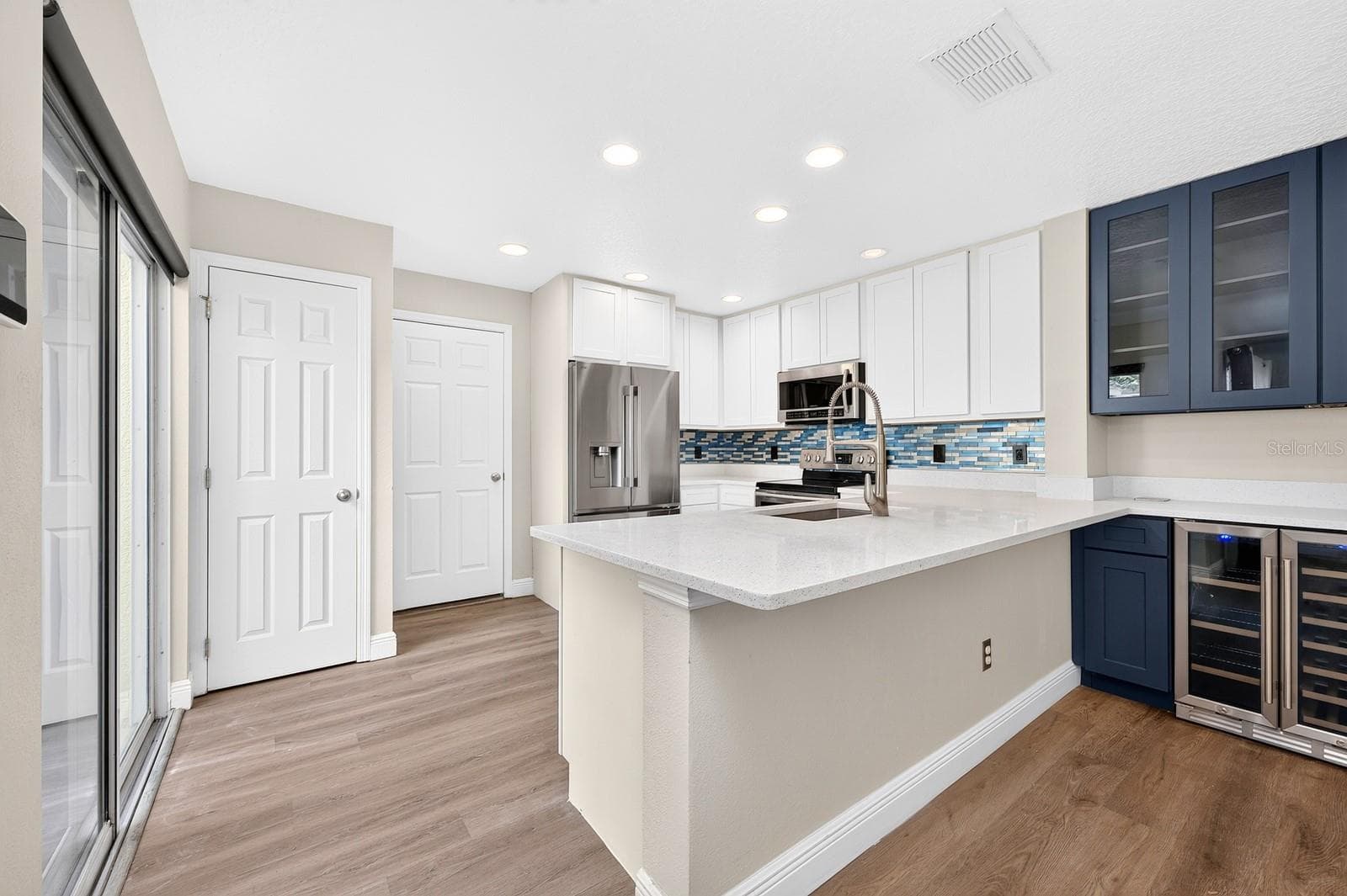 The Kitchen's modern cabinets and sparkling quartz counters blend seamlessly into the custom matching beverage bar--perfect for entertaining! - 13028 AUBURN COVE LN, ORLANDO