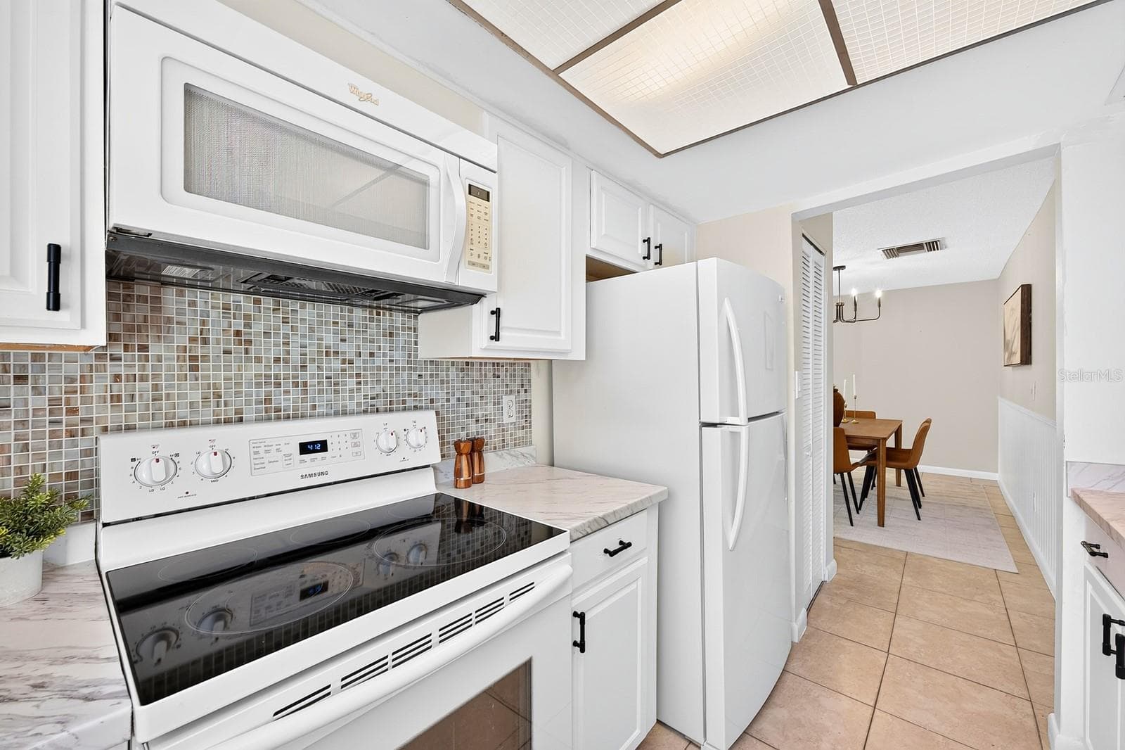 The Kitchen brings a fresh look with MARBLE-LOOK COUNTERTOPS, white cabinetry accented by NEW HARDWARE and a SLEEK TILE BACKSPLASH. - 543 HIBISCUS WAY #9C, ORLANDO