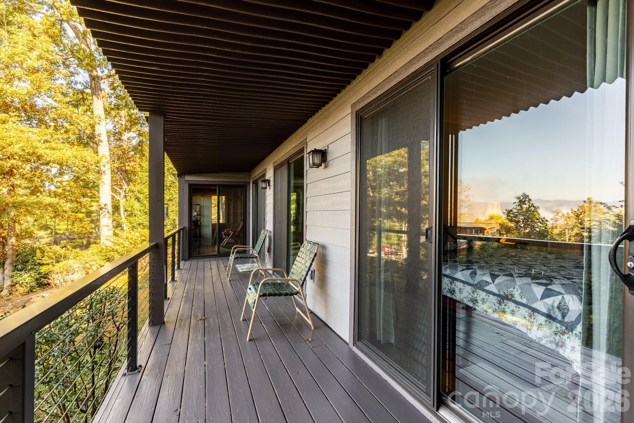 Expansive covered deck with durable decking, cable railing, and peaceful wooded surroundings. A wonderful place to relax and enjoy mountain living. - 524 Three Mile Knob Road, Pisgah Forest