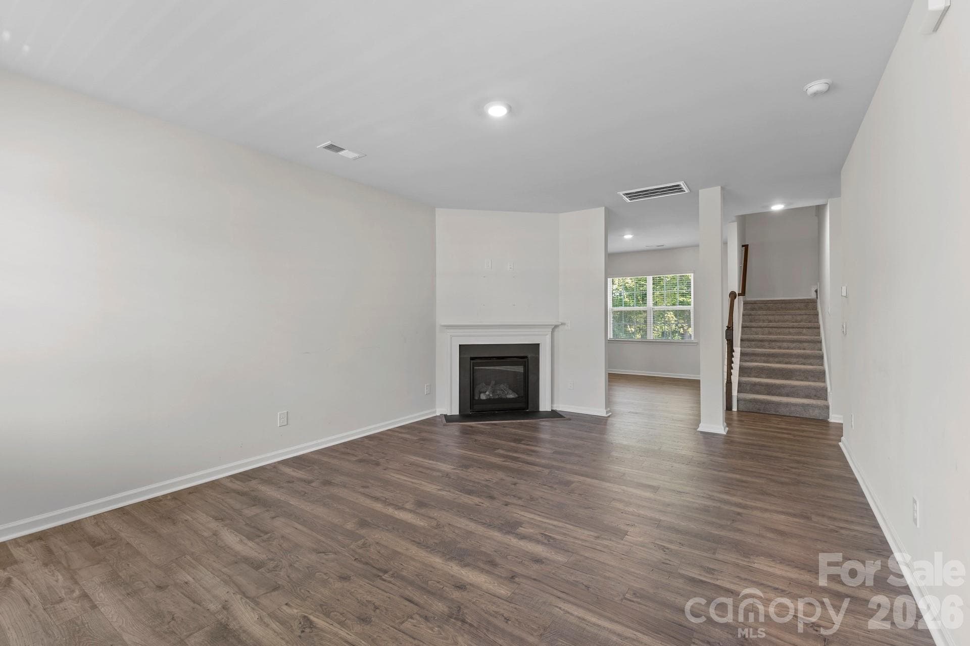 Unwind in the cozy living room, featuring low-maintenance LVP flooring and a warm gas-log fireplace with a classic slate surround and mantel. - 3741 Stanley Creek Drive, Mount Holly