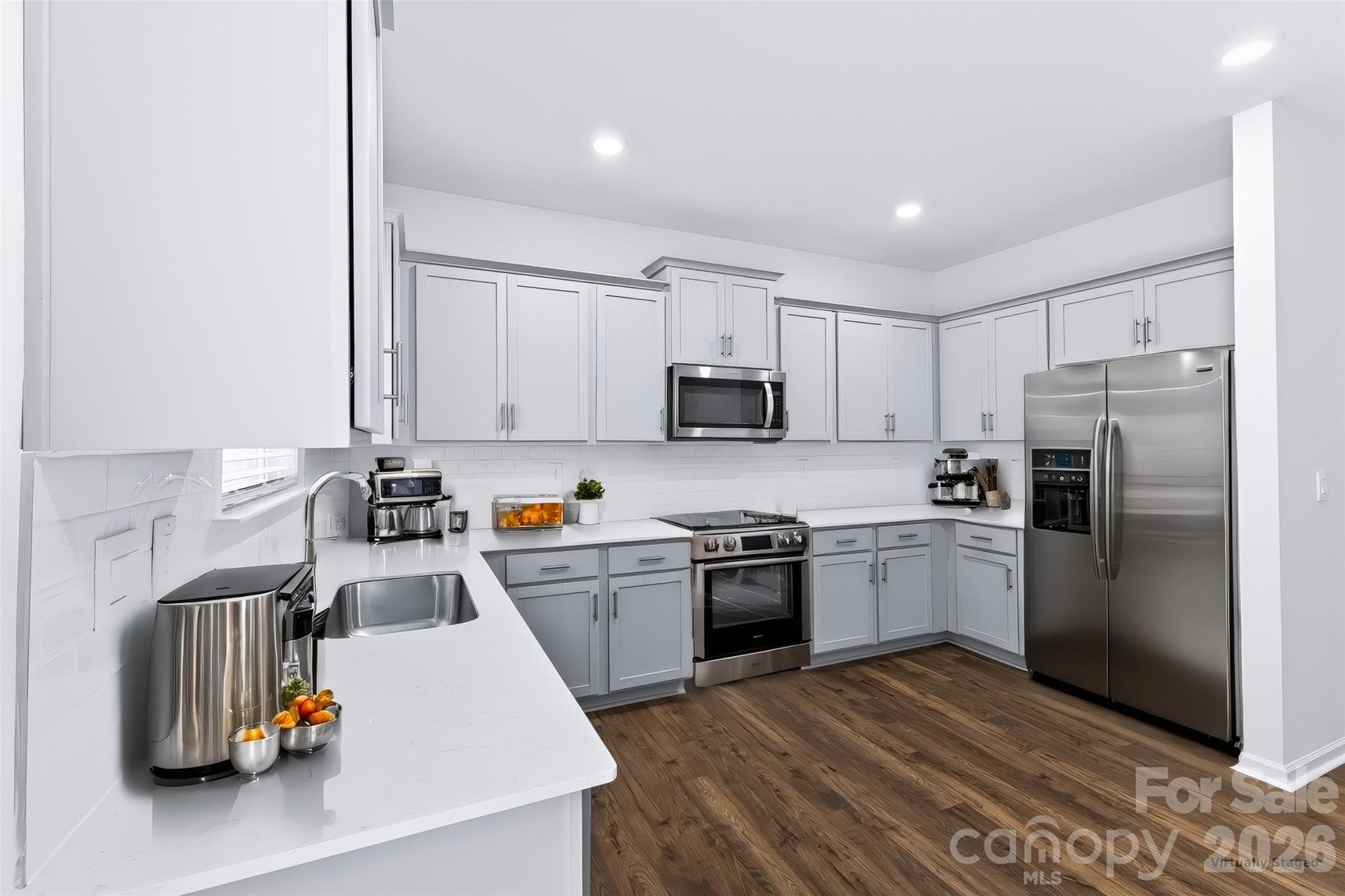 A spacious stainless steel undermount sink with a sleek pull-down faucet sits beneath a bright window overlooking the private, wooded backyard. - 3741 Stanley Creek Drive, Mount Holly