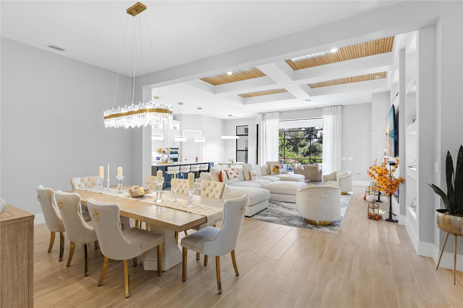 Bright, expansive open-concept living and dining areas featuring soaring ceilings, a coffered ceiling with inset wood trim, elegant architectural details, and expansive windows that fill the home with natural light. - 14726 EAGLE BRANCH DR, NOKOMIS