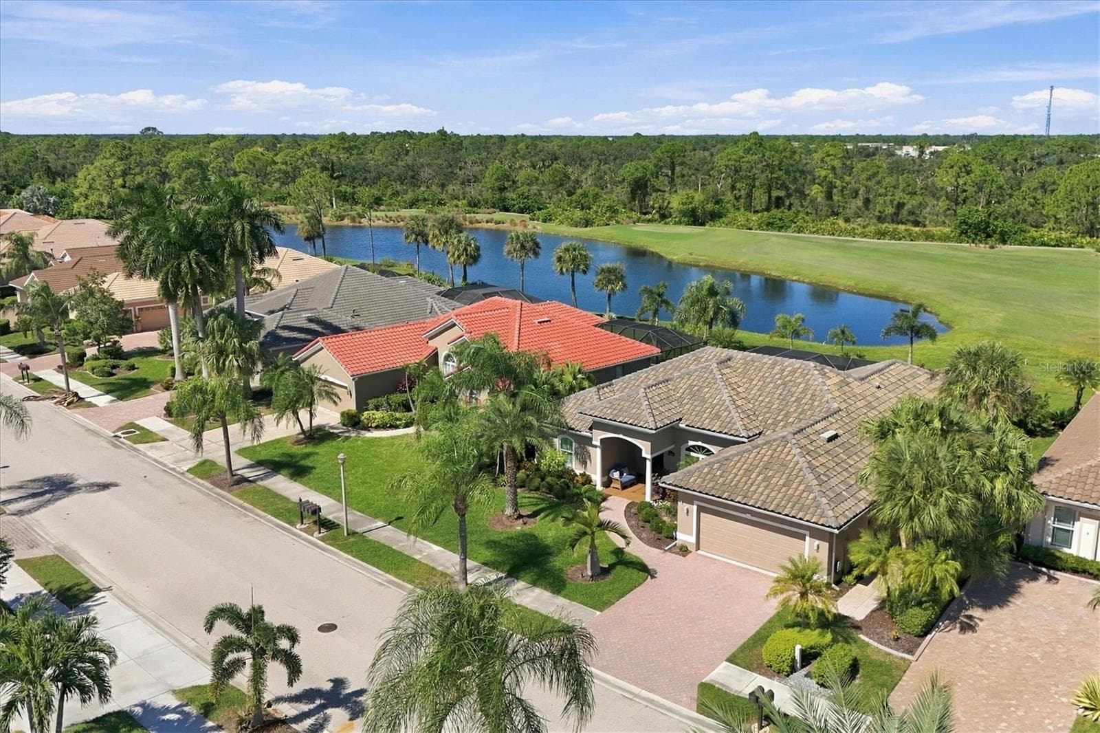Note lovely covered entry and handsome pavered driveway and walkway. Lake and fairway views of #2 of the Creek Course. Tile roof new 3/2024 - 5496 WHITE IBIS DR, NORTH PORT