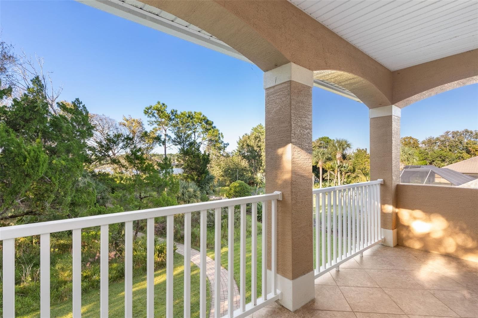 Step onto the private covered balcony and enjoy the peaceful natural surroundings, with glimpses of Emerald Lake through the trees. - 25 EMERALD LAKE CT, PALM COAST