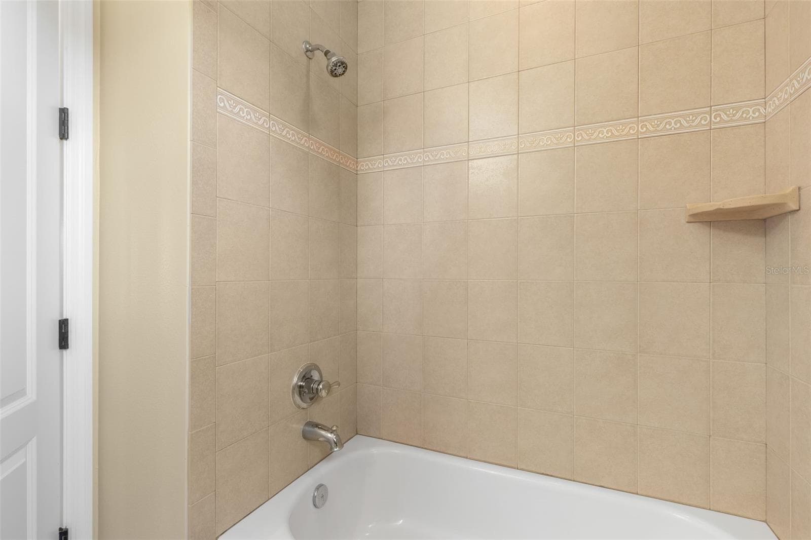 Decorative tile accents and a built-in corner shelf add thoughtful details to the upstairs bathroom's tub/shower combination. - 25 EMERALD LAKE CT, PALM COAST