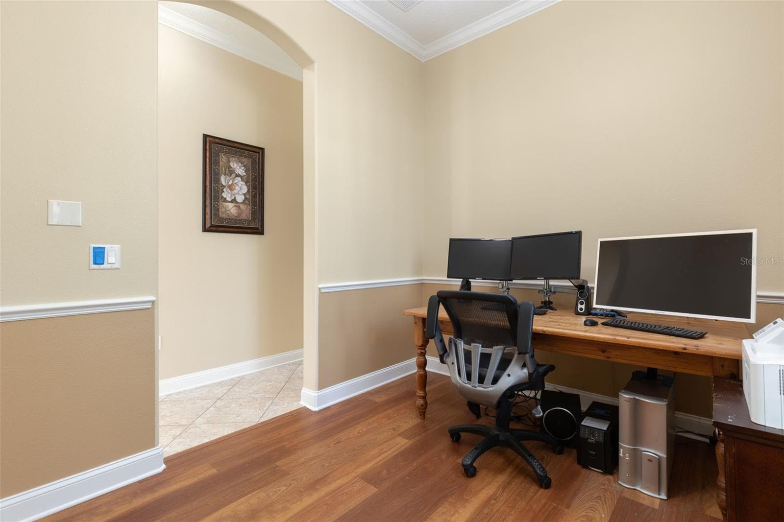 Another perspective of the office/den, highlighting the graceful arched entryway, crown molding, and chair rail detailing. - 25 EMERALD LAKE CT, PALM COAST