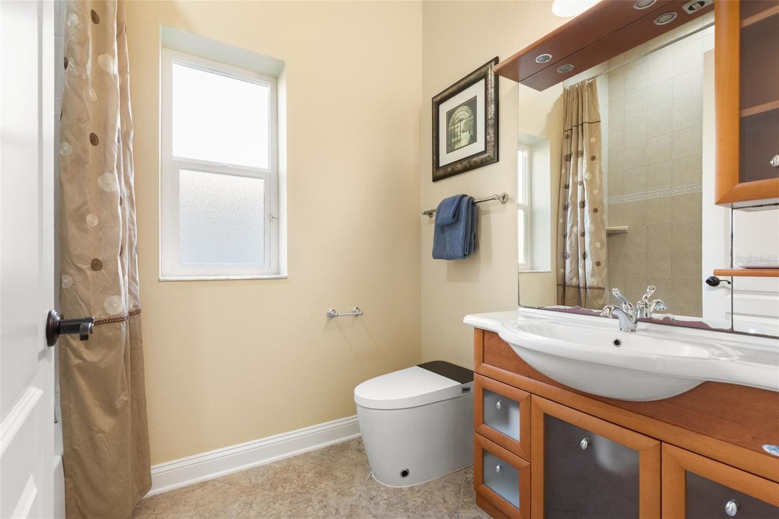 Italian-inspired first-floor guest bathroom featuring distinctive wood cabinetry, decorative tile flooring, and a tub/shower combination. - 25 EMERALD LAKE CT, PALM COAST