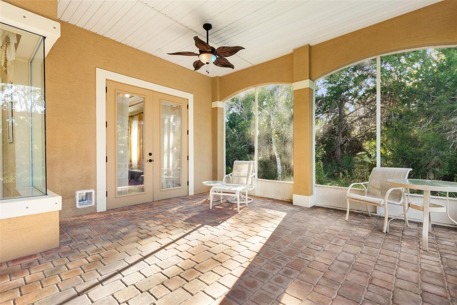 Screened lanai with paver flooring and French doors leading to the first-floor primary suite. - 25 EMERALD LAKE CT, PALM COAST